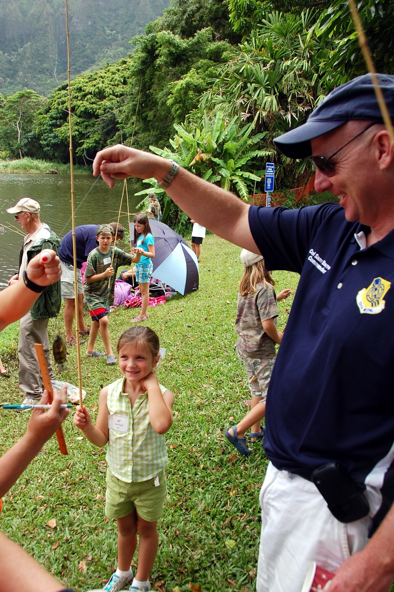 Air Force Col. Sam Barrett, 15th Wing commander, helps Julia Ford with her caught fish at the Friends of Hickam 12th Annual Keiki Fishing Tournament at Ho'omaluhia Botanical Garden June 1. (U.S Navy Photo/Chris Aguinaldo) 