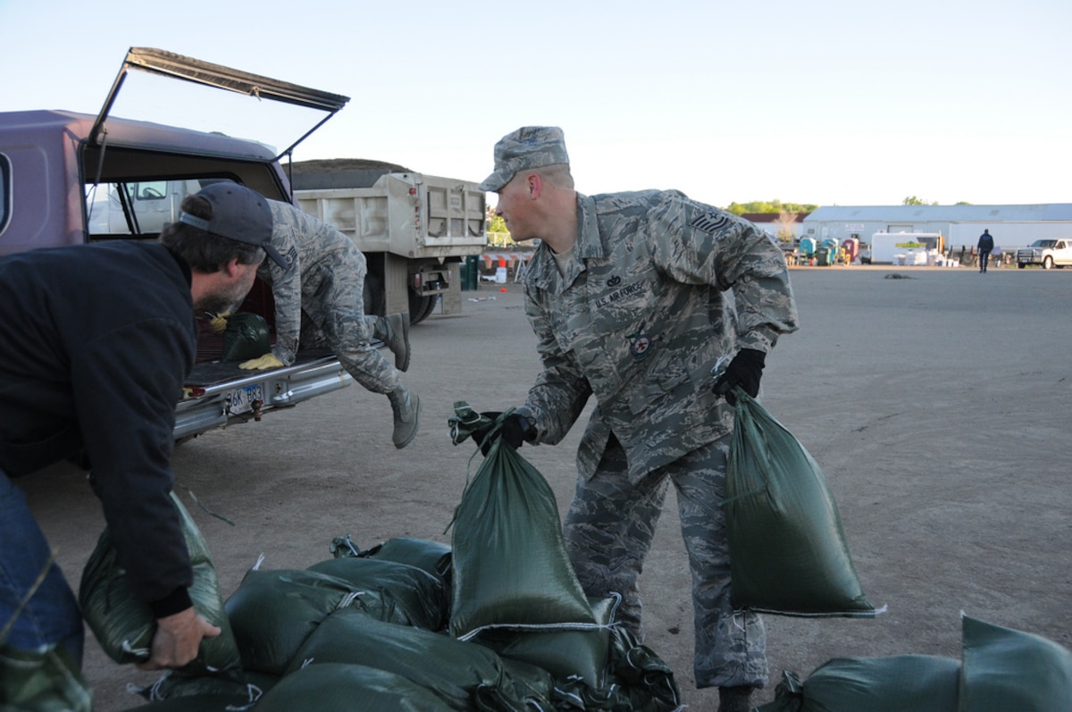 PIERRE, S.D. -- Tech. Sgt. Eric Hoogendoorn (right) and Staff Sgt. Adam Groff, both from the 114th Fighter Wing Civil Engineers, help Pierre resident Deloren Krieger load sandbags into his vehicle. To date, more than 900 Soldiers and Airmen from the South Dakota National Guard have been called to support the flood fighting efforts along the Missouri River. (SDNG photo by Capt. Michael Frye, 114th Fighter Wing Public Affairs Officer) (RELEASED)
