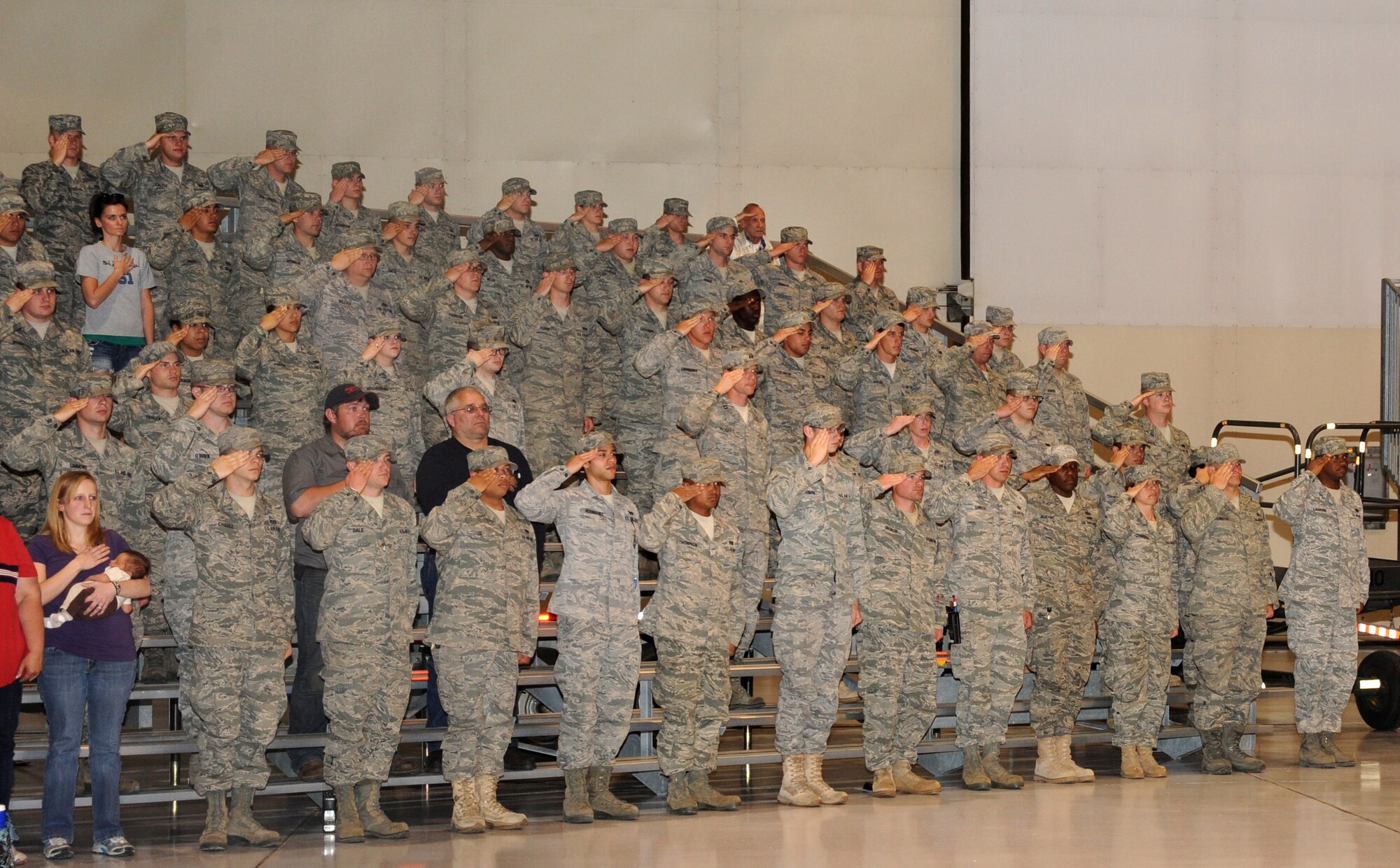 Airmen from Grand Forks Air Force Base salute the American flag during the playing of the National Anthem June 1 shortly before the beginning of the arrival ceremony of the RQ-4 Global Hawk to the base. The arrival marked the beginning of a new era of remotely piloted aircraft at the base, which will be maintained under Detachment 1, 9th Reconnaissance Wing. (U.S. Air Force photo by Senior Airman Amber Bennett)