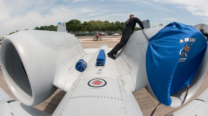 Senior Airman Kyle Myers, A-10 Demonstration Team crew chief, slips on a cover to one of the engines of the A-10C Thunderbolt II May 29. Airman Myers covers the engines to prevent foreign objects from flying into them. (U.S. Air Force photo by Airman 1st Class Nicholas Benroth/Released) 