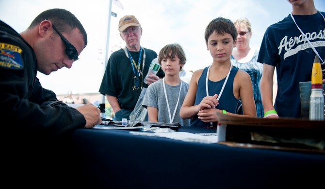 JONES BEACH STATE PARK, N.Y. -- Staff Sgt. Benjamin McIntosh, A-10 East Demonstration Team engine specialist, signs autographs during an air show May 29. The demo team took time to greet, answer questions and take photos with air show enthusiasts whenever they weren’t preparing for a flight. (U.S. Air Force photo/Staff Sgt. Jamal D. Sutter)(RELEASED)