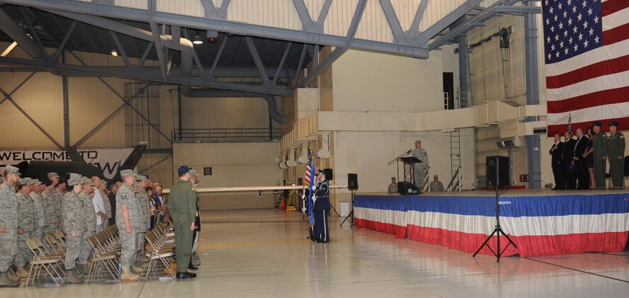 Airman from Grand Forks Air Force Base and other ceremony attendees stand before the playing of the National Anthem during the arrival ceremony of the RQ-4 Global Hawk to the base June 1. The arrival marked the beginning of a new era of remotely piloted aircraft at the base, which will be maintained under Detachment 1, 9th Reconnaissance Wing. (U.S. Air Force photo by Senior Airman Amber Bennett)