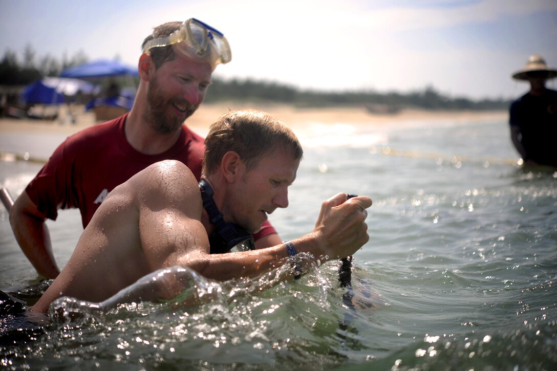 U.S. Army Staff Sgt. Michael Meeks, right, and underwater anthropologist Andrew Pietruszka, left, plant a metal stake to mark an excavation grid point during an underwater recovery mission, Thua Thien Hue, Vietnam, May 21, 2011. Meeks and Pietruszka are assigned to the Joint POW/MIA Accounting Command.