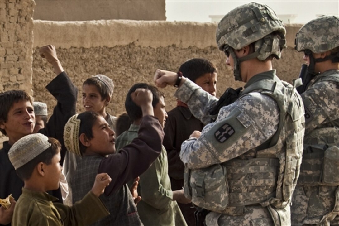 U.S. Army soldiers bump fists with Afghan children during a mission to Kuchi village, Afghanistan, May 27, 2011. The soldiers, assigned to the 1775th Military Police Company, were there to distribute radios and flyers, and to evaluate the needs of residents. 
