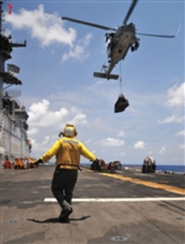 U.S. Navy Petty Officer 3rd Class Rodolfo Lopez signals an MH-60 Seahawk helicopter with Helicopter Sea Combat Squadron 23 to lower a pallet of supplies onto the flight deck of the amphibious assault ship USS Boxer (LHD 4) during a replenishment-at-sea with the Military Sealift Command underway replenishment oiler USNS Patuxent (T-AO 201) in the Gulf of Aden on May 19, 2011.  The Boxer supported maritime security operations and theater security cooperation efforts in the U.S. 5th Fleet area of responsibility.  