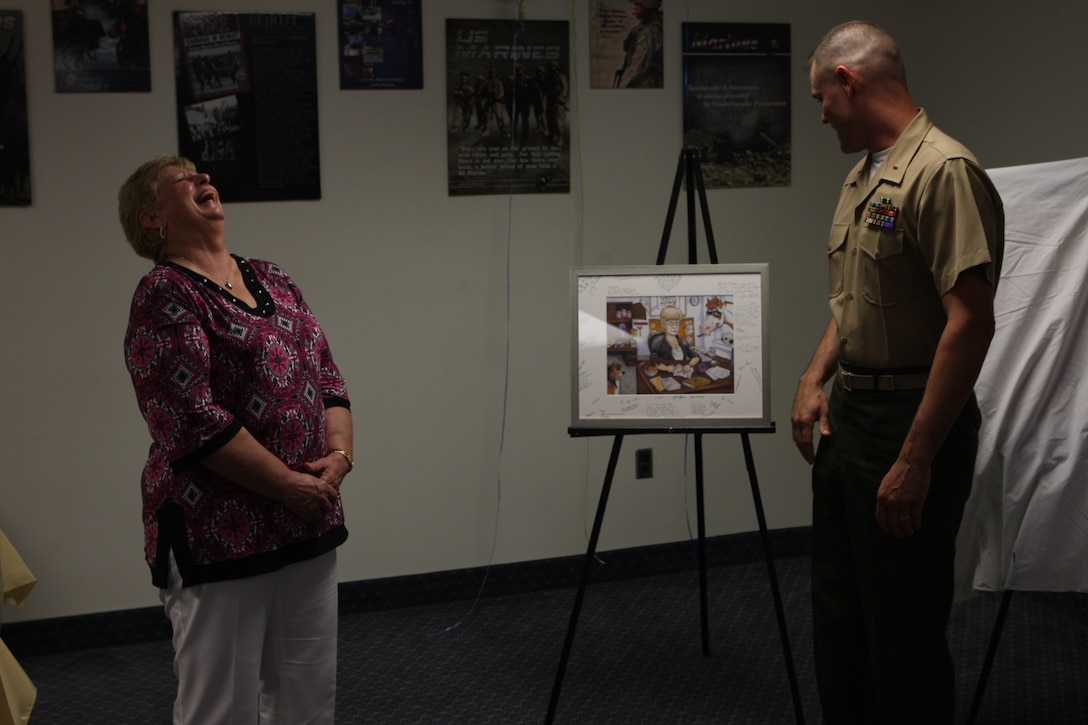 Virginia Court, deputy director of the Marine Corps Combat Service Support Schools Personnel Administration Center, reacts after being presented with a self-portrait by Chief Warrant Officer 2 Michael McCarr, director of the MCCSSS PAC, during Court’s retirement at the Camp Johnson Bachelor Officers’ Quarters, June 3. Court retired after serving 40 years combined federal service for the Department of Defense, 35 of those years spent with the Marine Corps.