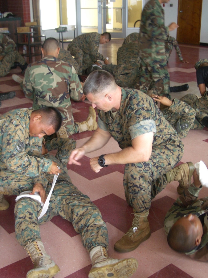 Staff Sgt. Michael Heller, a member of the Security Cooperation team, U.S. Marine Corps Forces, South, assists with the instruction of applying a field dressing during a Security Cooperation engagement with Cuerpo Infanteria de Marina (CIM) of Panama's National Sea and Air Service (SENAN), June 2, 2011. (Official USMC photo/released)