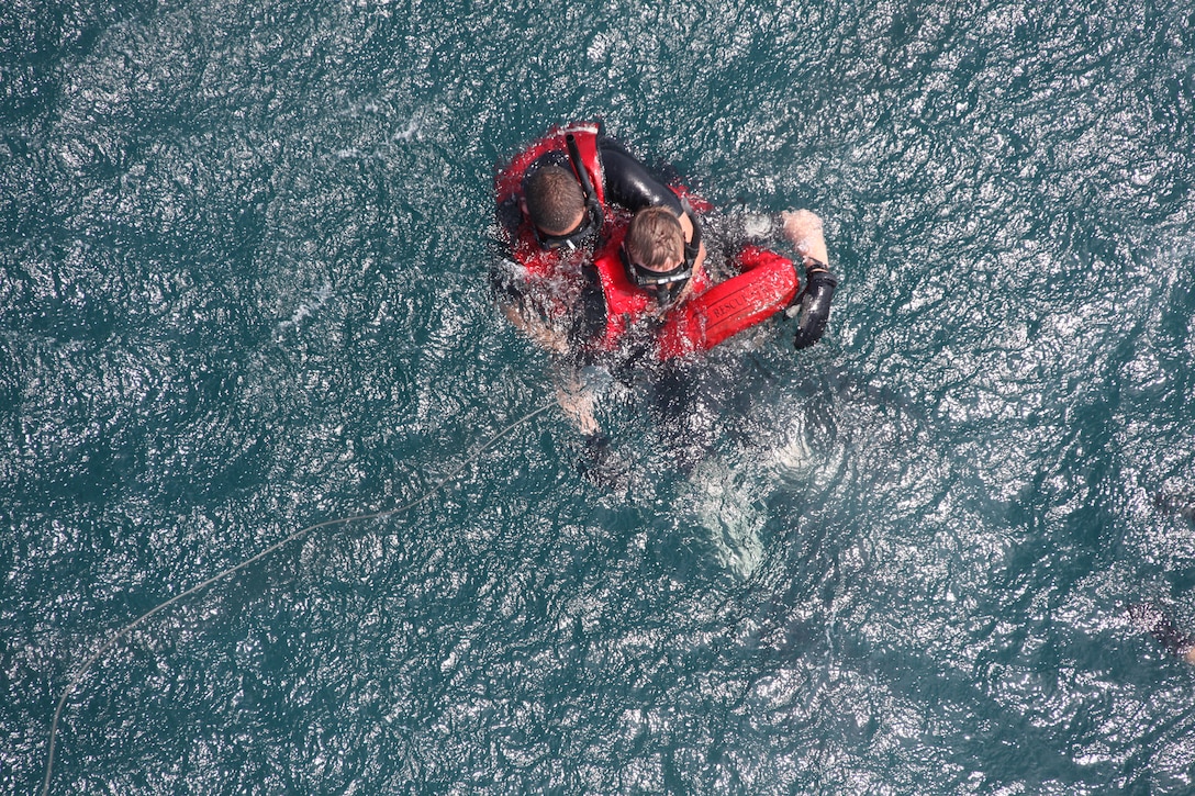 Seaman Michael S. Harris puts a rescue strop onto a simulated casualty in the ocean off the coast of Fort Macon during the swimmer deployment portion of Marine Transport Squadron 1 search and rescue certification testing June 3.  Harris is training to become a rescue swimmer with VMR-1.