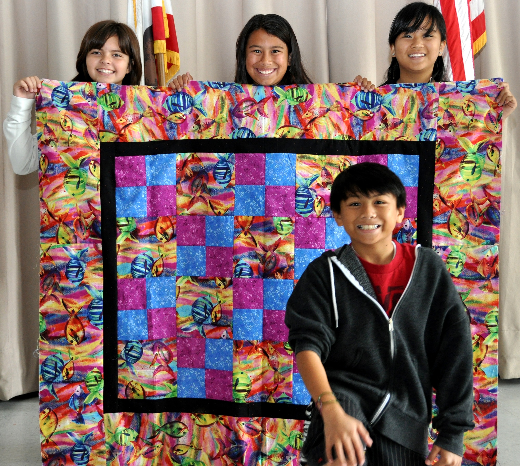 Students, Morgan Viega, left, Camille Lara, middle, Angelika Gomez, right, and Kinsley Florentine, bottom, from Linda Lawvey's fifth-grade class hold up one of six completed quilts June 1 at Scandia Elementary School. The quilts will be sent to children who have been impacted by the March 11 earthquake and tsunami in Japan. 