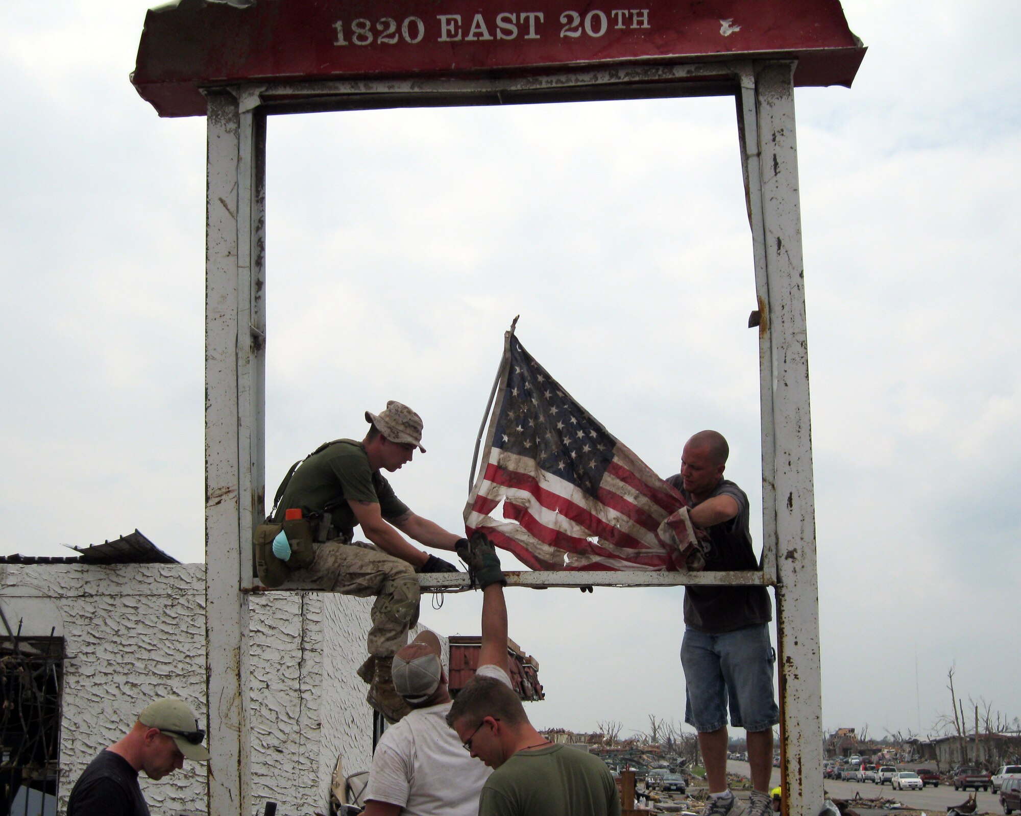 Volunteers fly a tattered American flag from a street sign in Joplin, Mo., May 28, 2011. Sixteen Airmen from Altus Air Force Base delivered donations to Joplin, as well as helped search for survivors May 27-28. (Courtesy photo)                         