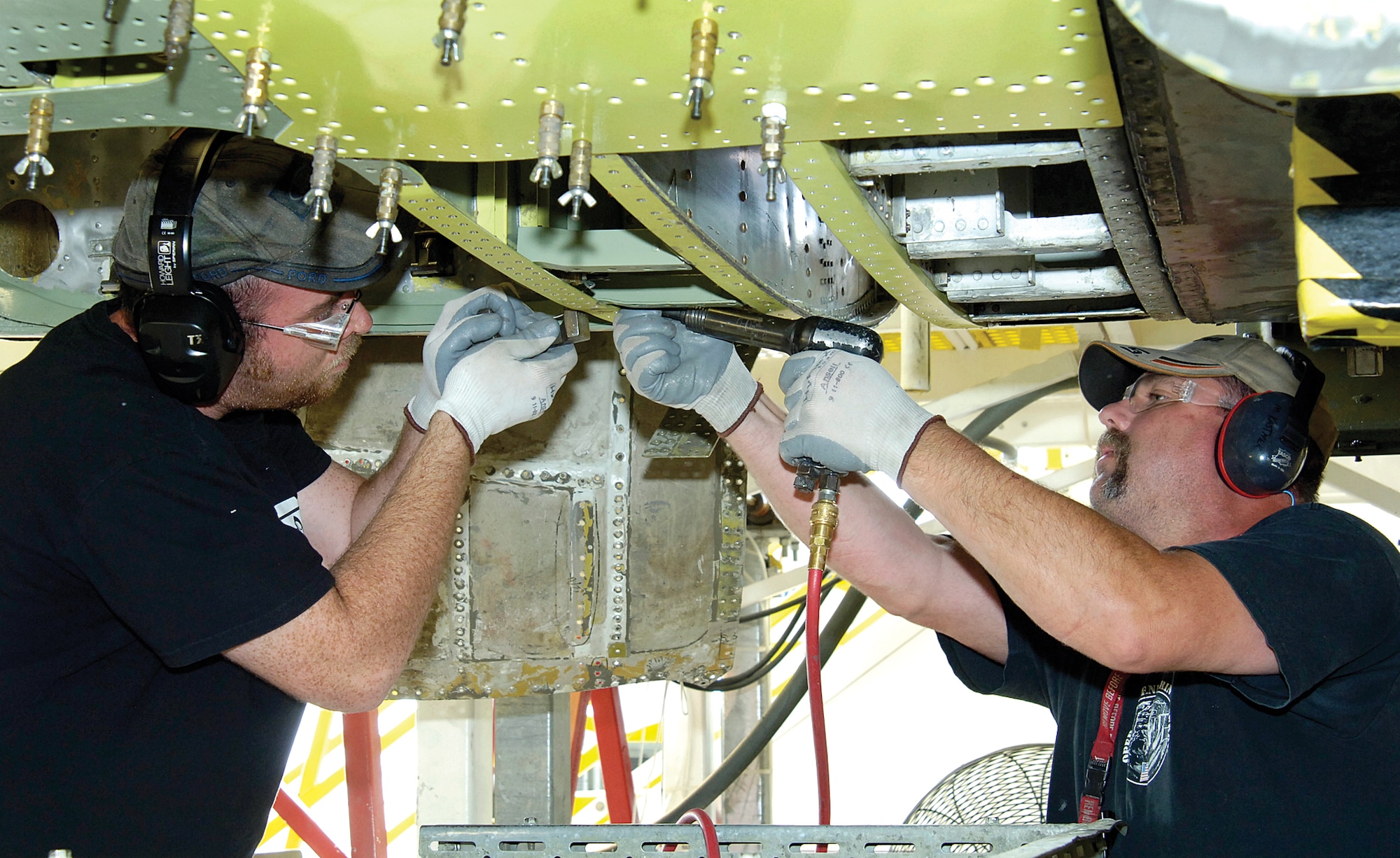 Tinker sheet metal mechanics Joseph Cooley, left, and Matthew Kastner work corrosion on a B-52 crew entry hatch area. The men are members of the 565th Aircraft Maintenance Squadron, 76th Aircraft Maintenance Group. (Air Force photo by Margo Wright)