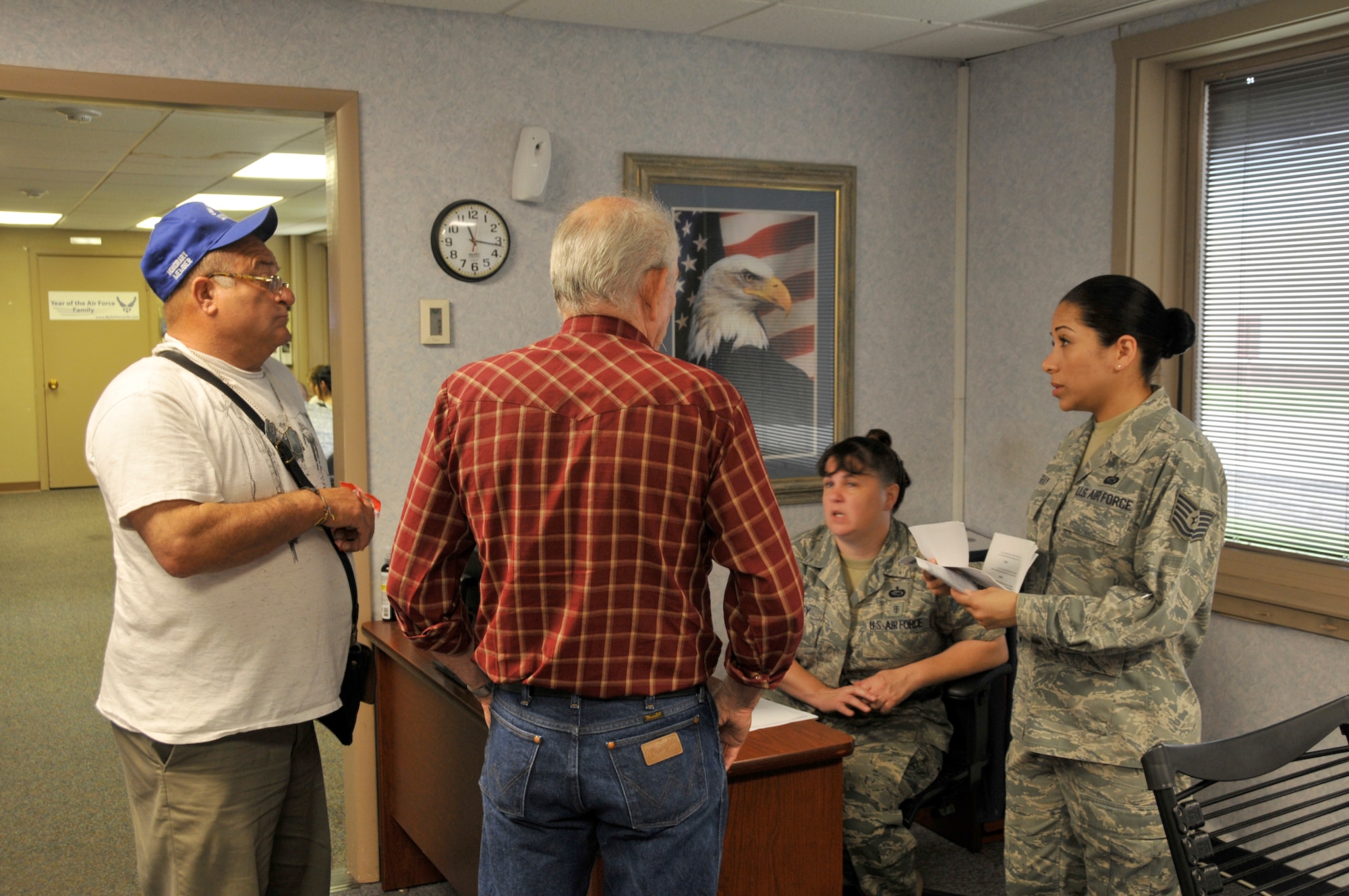 Tech. Sgt. Jessica Gray, customer support non-commissioned officer in-charge, and Staff Sgt. Kerry Godfrey, customer support supervisor, review a veteran's paperwork in the Customer Service and ID Card office. (Air Force photo by Brian Schroeder)