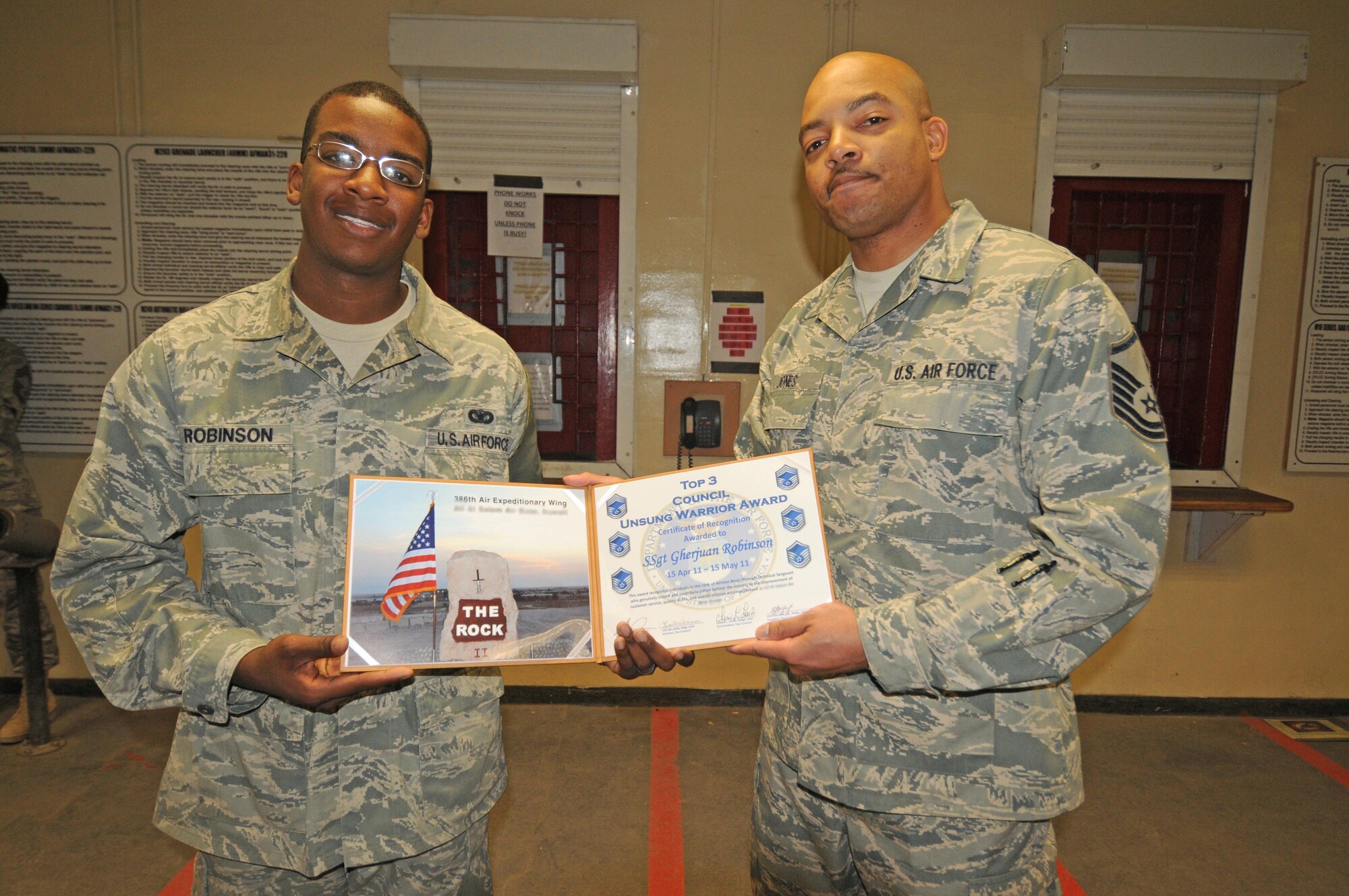 Staff Sgt. Gherjuan Robinson, a Defender with the 386th Expeditionary Security Forces Squadron is presented the 386th Air Expeditionary Wing Top III Council's Unsung Warrior award by Master Sgt. Marcus Jones. This award is given in two categories, Airman and NCO, to individuals who "genuninely inspire and contribute (often behind the scenes) to the improvement of customer service, quality of life and overall mission accomplishment at the 386th AEW." (U.S. Air Force photo by Staff Sgt. Patrice Clarke)