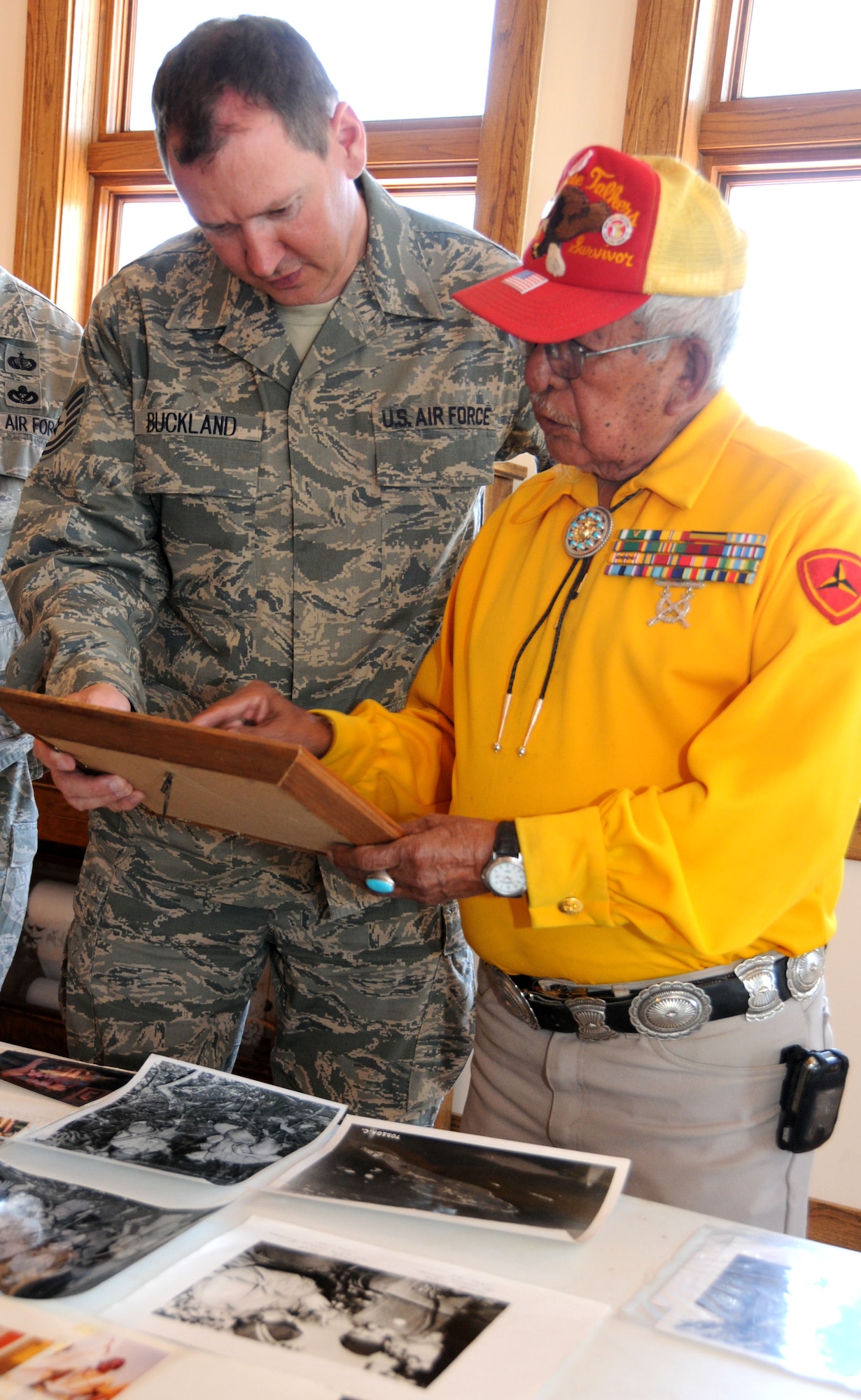 Bill Toledo, an original Navajo "Code-Talker" from World War II, discusses an old photo of himself with Tech Sgt. Gareth Buckland, Broadcaster, 113th Wing Public Affairs, District of Columbia Air National Guard, before Toledo's speech to members of the 113th Wing in Gallup, N.M., June 2, 2011.  The 113th Wing members are in Gallup and Window Rock, Ariz., as part of the Innovative Readiness Training, a civil-military affairs program linking military units with civilian communities for humanitarian projects.  (U.S. Air Force Photo by Tech Sgt. Craig Clapper)   
