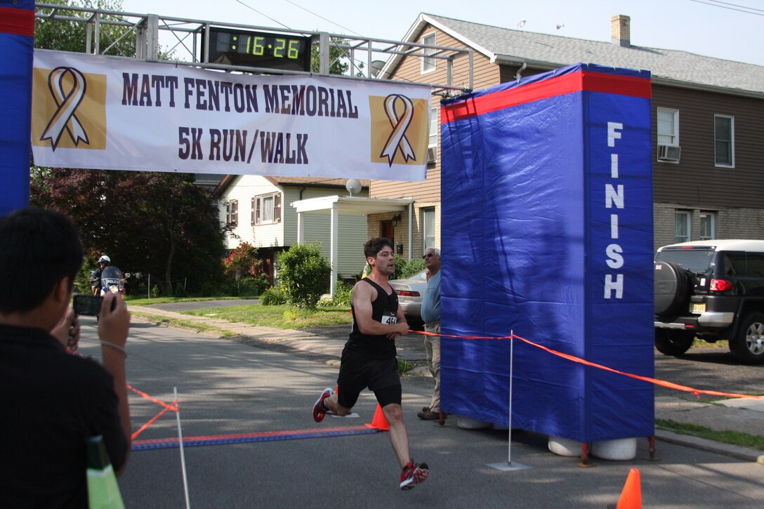 Michael Fonder, a participant in the first Sgt. Matthew Fenton Memorial 5K Race, crosses the finish line, June 5. Fonder was the first to finish the five-kilometer run in 16 minutes and 26 seconds.
