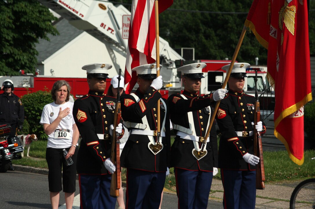 A color guard from 2nd Battalion, 25th Marine Regiment from Garden City, N.Y., presents the colors in front of more than 500 runners as Diane Fenton, mother of Sgt. Matthew Fenton, stands behind them. The town held the first Sgt. Matthew Fenton Memorial 5K Race on June 5 to honor Fenton, who died from injuries sustained while conducting combat operations in Fallujah, Iraq, in support of Operation Iraqi Freedom in 2006.