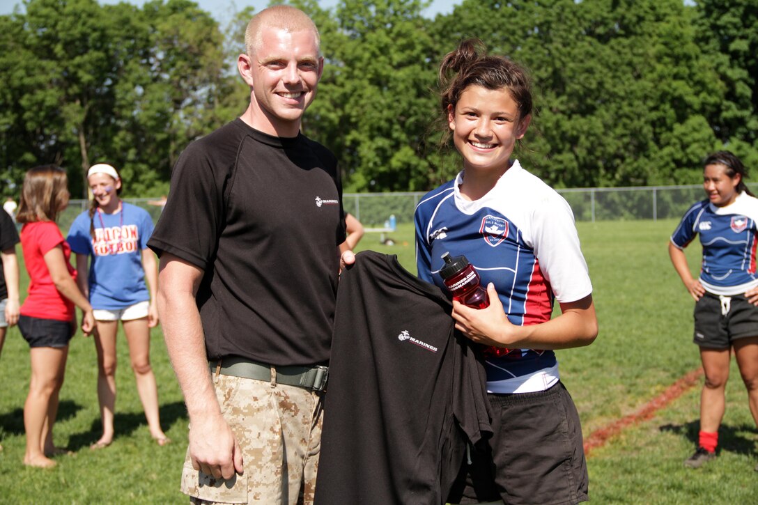 Sgt. Zachary J. Kurki, 24, from Hueson, Wis., presents some Marine memorabilia to Genna Joyce, Armstrong Falcons, for being named their Warrior of the Match following the Girls Division 1 championship game of the Minnesota Amateur Rugby Foundation Tournament at Gordy Aamoth Jr., Memorial Stadium June 5. Armstrong beat the Orono Nightmares 5-0 for the state title. Kurki is a recruiter out of the Bloomington, Minn., office. For additional imagery from the event, visit www.facebook.com/rstwincities.