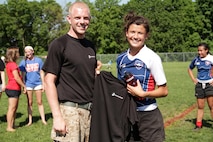 Sgt. Zachary J. Kurki, 24, from Hueson, Wis., presents some Marine memorabilia to Genna Joyce, Armstrong Falcons, for being named their Warrior of the Match following the Girls Division 1 championship game of the Minnesota Amateur Rugby Foundation Tournament at Gordy Aamoth Jr., Memorial Stadium June 5. Armstrong beat the Orono Nightmares 5-0 for the state title. Kurki is a recruiter out of the Bloomington, Minn., office. For additional imagery from the event, visit www.facebook.com/rstwincities.