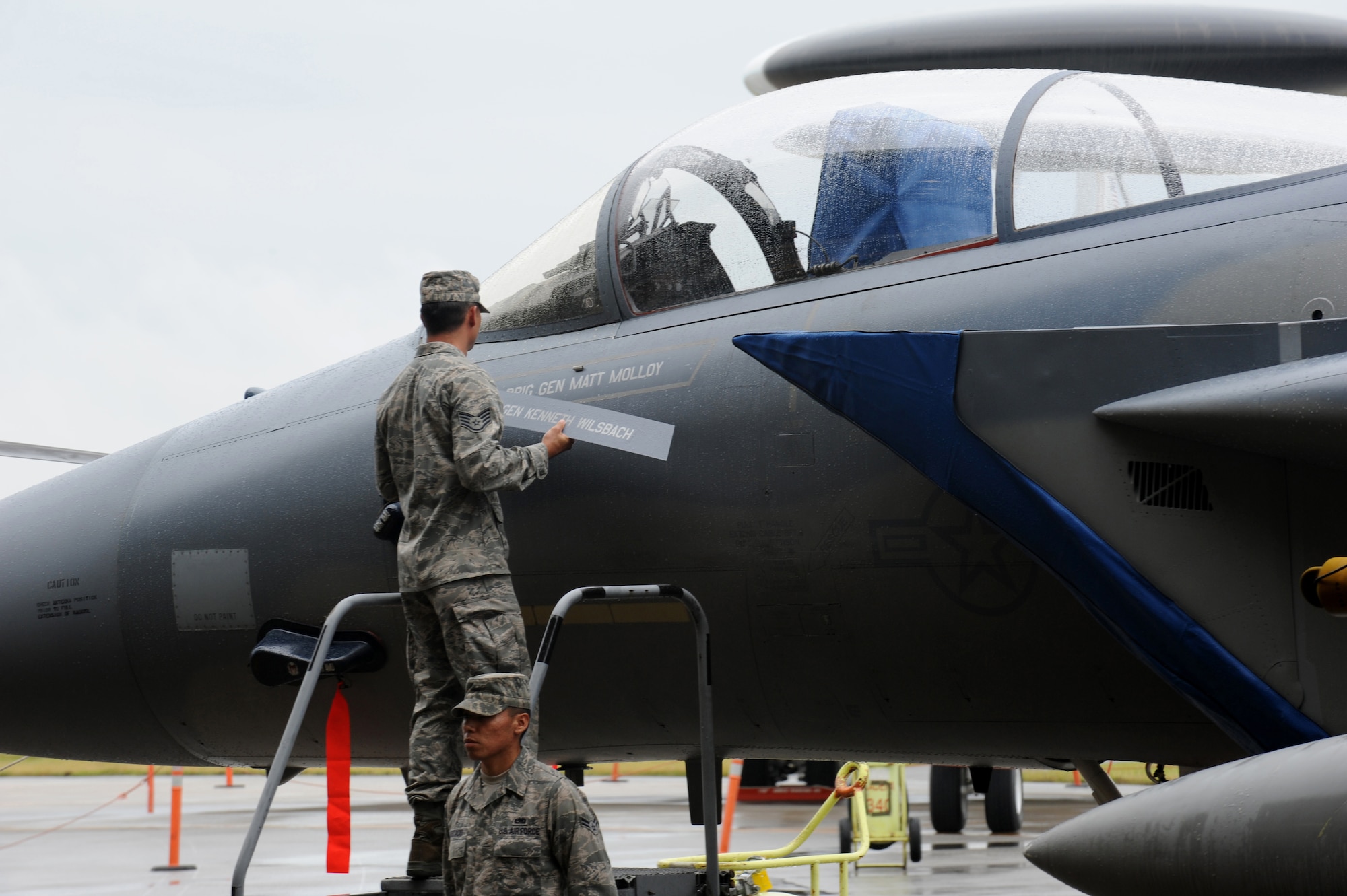 Dedicated crew chiefs replace the name plate on the 18th Wing commander's F-15 Eagle during the 18th Wing change of command ceremony at Kadena Air Base, Japan, June 3. The changing of the name on the aircraft signifies the relinquishing of command of the wing from Brig. Gen. Ken Wilsbach to the new wing commander, Brig. Gen. Matt Molloy. (U.S. Air Force photo/Junko Kinjo)
