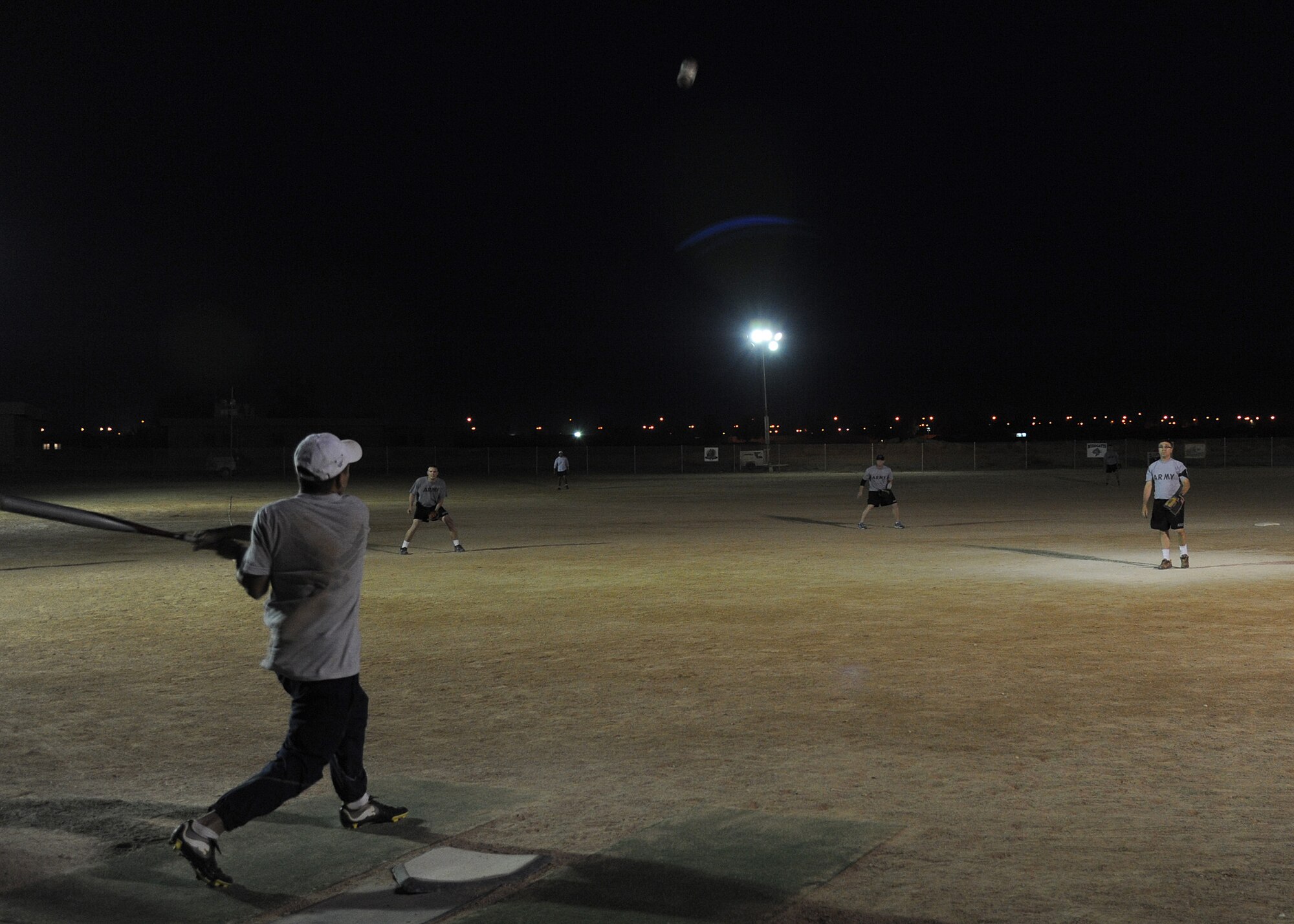 U.S. Air Force Senior Airman Jacob Gibbons, 532nd Expeditionary Operations Support Squadron, hits a softball to the outfield during a game May 27, 2011, at Al Asad Air Base, Iraq. The service members assigned to the installation regularly work 12-hour shifts, seven days a week. Playing a game of softball helps them maintain high morale at a location that sees operations come to a stand-still during dust storms in western Al Anbar Province. (U.S. Air Force photo by Senior Airman Tristin English)