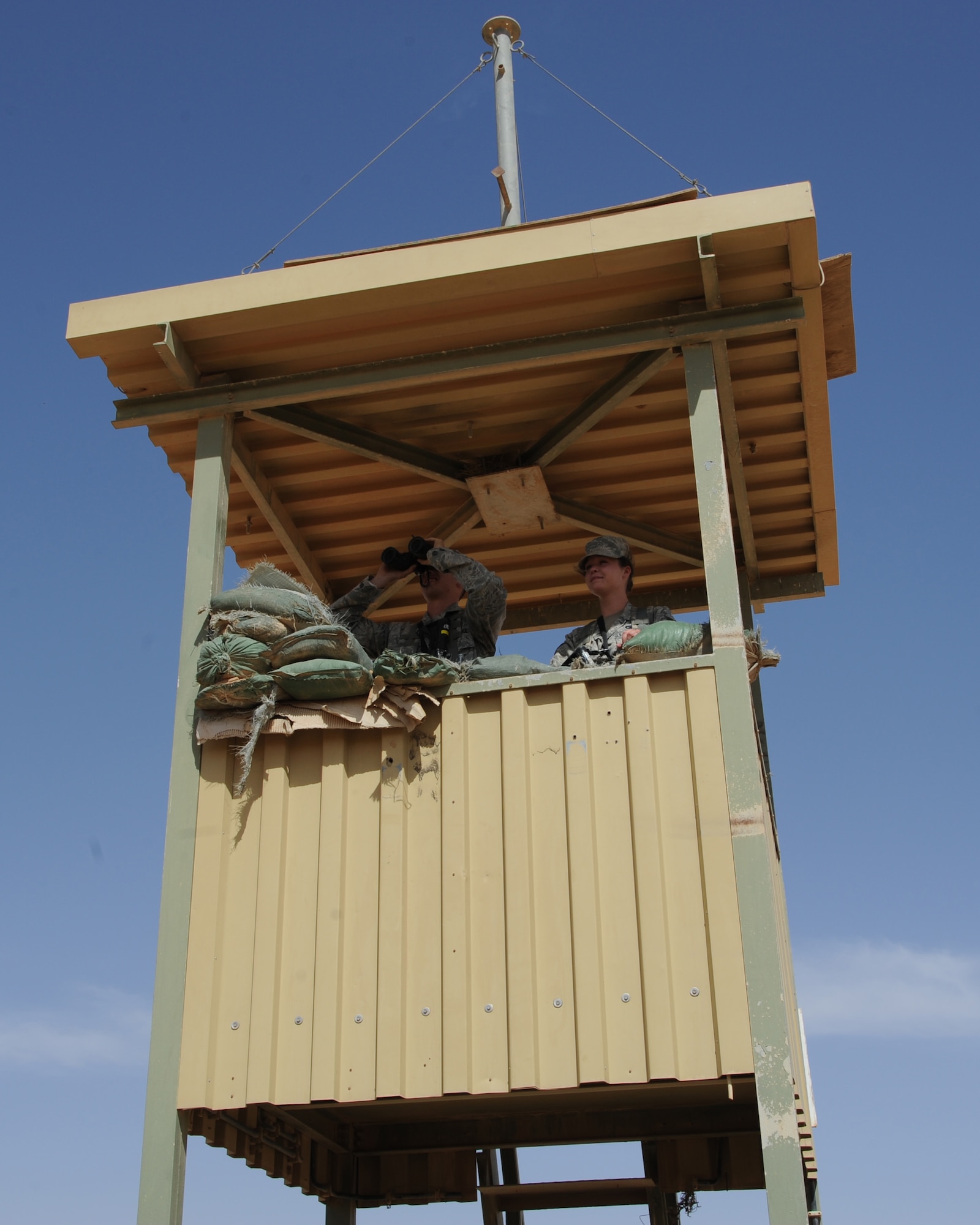 U.S. Air Force Airmen 1st Class Sean Bard, with binoculars, and Madeline Kappes, right, both deployed to the 532nd Expeditionary Operations Support Squadron security forces flight, help provide a ring of security around the largest runway in the Iraqi desert May 27, 2011, at Al Asad Air Base, Iraq. If something suspicious is seen while in the observation post, a report is sent and a quick reaction force responds. (U.S. Air Force photo by Senior Airman Tristin English)
