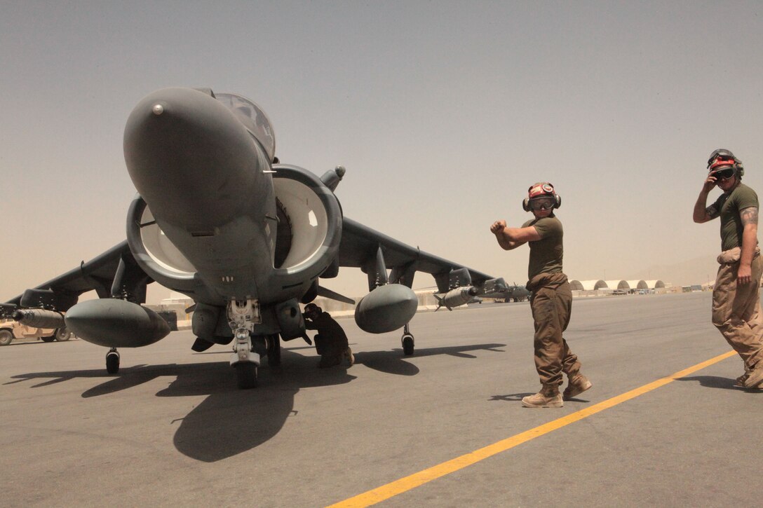 Lance Cpl. Peter E. Clary, at left under aircraft, a Moscow, Idaho, native; Lance Cpl. Kyle M. Rowe, a Troy, Ohio, native; and Cpl. Zachary G. Mills, an Orlando, Fla., native, all Marine Attack Squadron 513 ordnance technicians, disarm one of the squadron’s AV-8B Harriers before it returns to the docking area at Kandahar Airfield, Afghanistan, June 6.