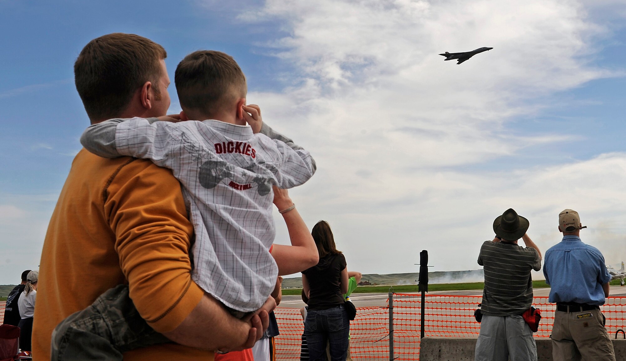 Visitors watch as a B-1B Lancer flies over the 2011 Dakota Thunder airshow at Ellsworth Air Force Base, S.D., June 4, 2011.  The B-1 is a long-range, multi-role, heavy bomber capable of flying over 900 mph. (U.S. Air Force photo/Staff Sgt. Marc I. Lane)