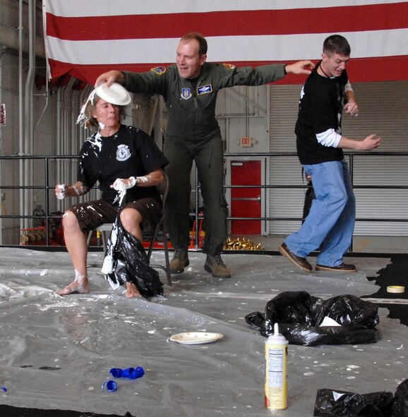 As his topcover ducks away, Lt. Col. John Welch, 940th Wing Director of Staff, plops a pie on the head of Lt. Col. Abigail Uptegraff, the wing's executive officer.  The pie-in-the-face fundraiser was part of the fun and games at the 940th Wing's annual picnic,  June 5, 2011, at Beale Air Force Base, Calif.  (U.S. Air Force photo by Tech Sgt Kenneth McCann/Released)  