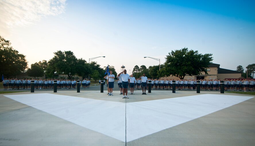 Airmen from the 23rd Maintenance Group stand in formation during the playing of reveille before a 1.5-mile morale run at Moody Air Force Base, Ga., June 3. After hosting the Maintenance Professional of the Year event, the 23rd MXG rewarded the squadrons with a sports day as a way to boost morale. (U.S. Air Force photo/Airman 1st Class Joshua Green)(RELEASED)
