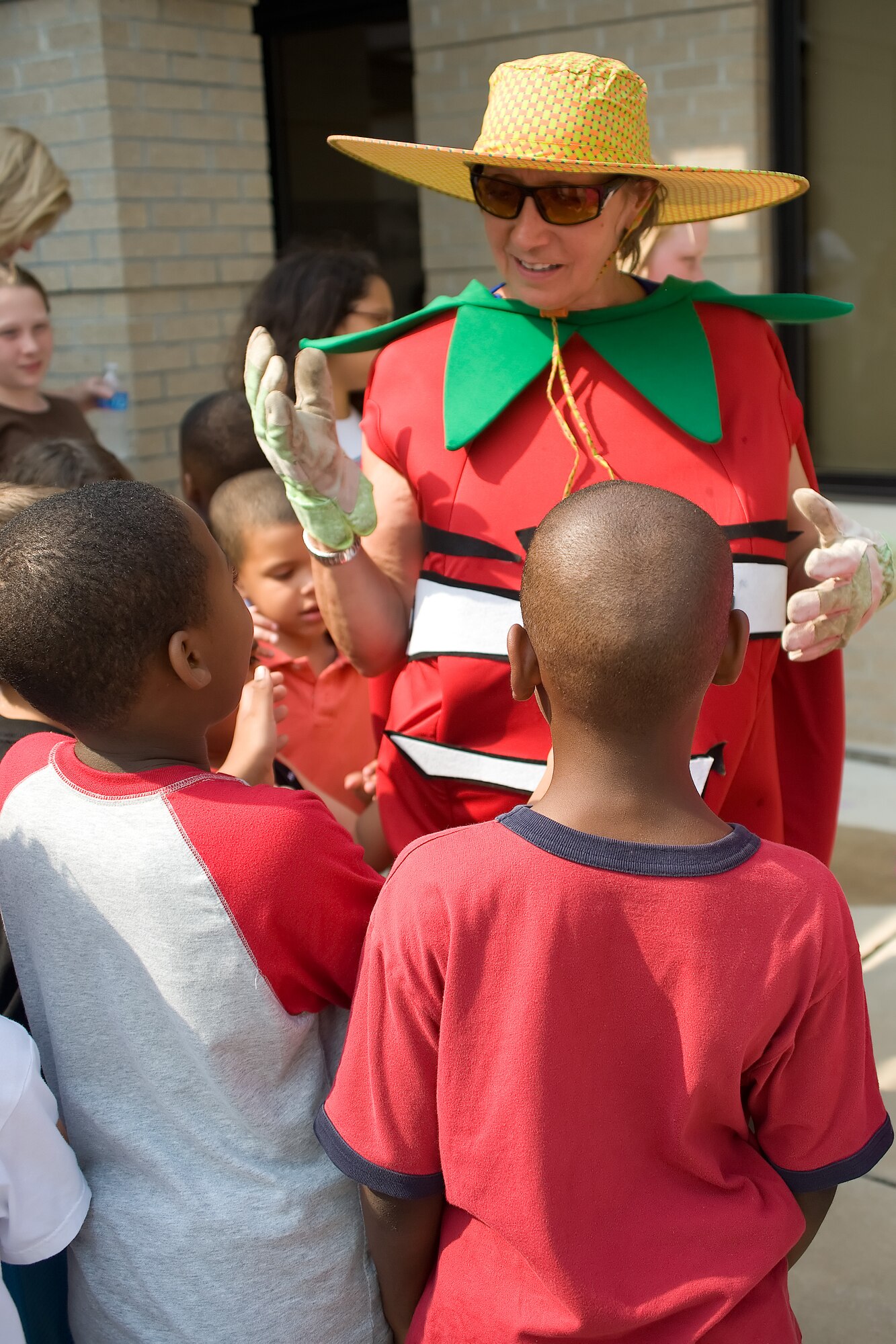 The Rebel Tomato (Kate Jennings), a HAWC mascot for a healthy diet, shares jokes with the children who helped plant the community garden June 1, 2011, at Dover Air Force Base, Del. “How do you fix a broken pizza?,” said Ms. Jennings. “Tomato paste” she answered.