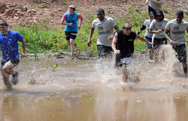 SPANGDAHLEM AIR BASE, Germany -- Competitors run through a pond during the Saber Endurance Challenge here June 3. Teams of five were judged on team creativity, guessing their time and money raised. Students from Bitburg High School guessed their time closest within four minutes of estimated completion. Team Soup Kitchen from the 52nd Equipment Maintenance Squadron was awarded most creative, and Team MDSS from the 52nd Medical Group raised the most money. The challenge was hosted by the Tier II council and raised money for the Wounded Warrior Project at Landstuhl Regional Medical Center, Germany. (U.S. Air Force photo/Airman 1st Class Brittney Frees)