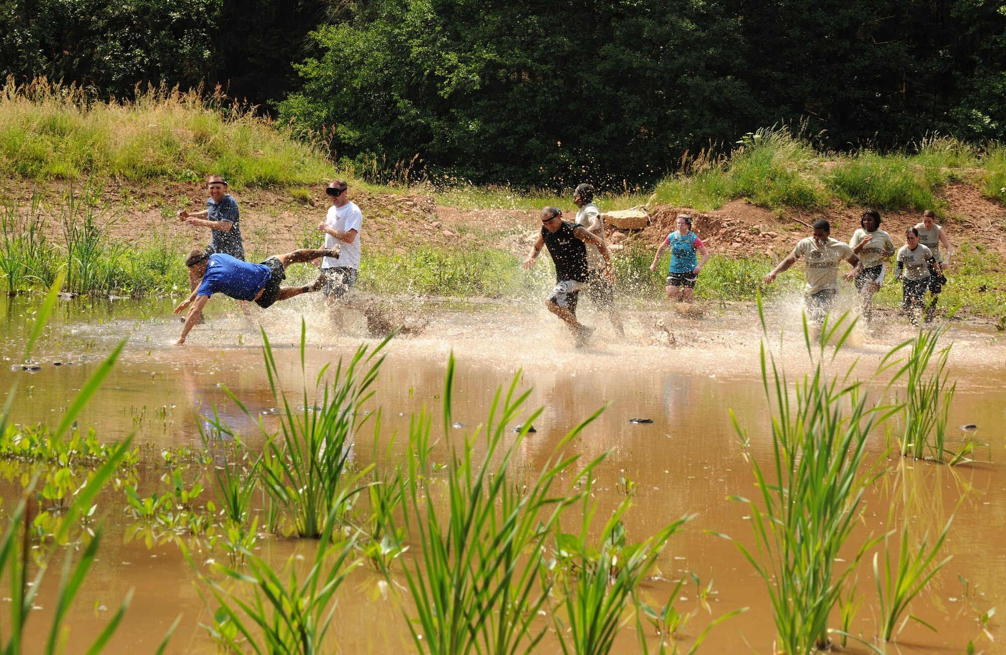 SPANGDHALEM AIR BASE, Germany – Competitors run through a pond during the Saber Endurance Challenge here June 3. Teams of five were judged on team creativity, guessing their time and money raised. Students from Bitburg High School guessed their time closest within four minutes of estimated completion. Team Soup Kitchen from the 52nd Equipment Maintenance Squadron was awarded most creative, and Team MDSS from the 52nd Medical Group raised the most money. The challenge was hosted by the Tier II council and raised money for the Wounded Warrior Project at Landstuhl Regional Medical Center, Germany. (U.S. Air Force photo/Senior Airman Nathanael Callon)