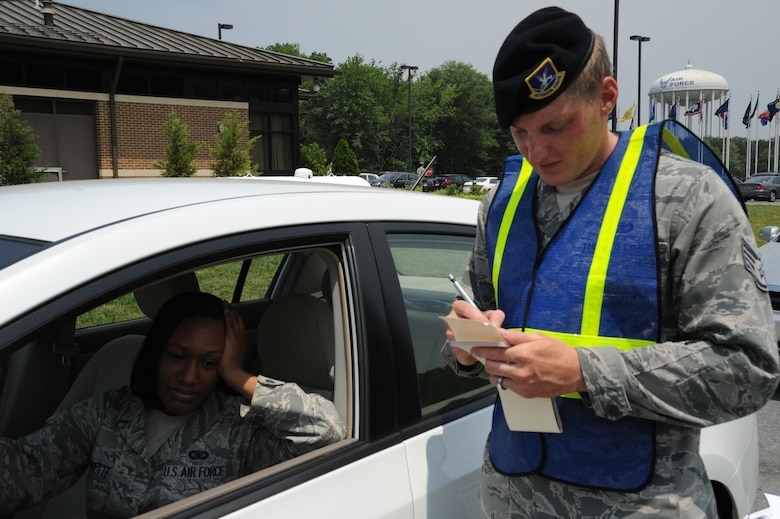 Staff Sgt. Daniel Hadley, 11th Security Forces Squadron crime prevention NCO, simulates writing a ticket for Senior Airman Desantis C. Symonette, 11 SFS Visitor Control Center security clerk during a seatbelt and cell phone selective enforcement check May 26. (U.S. Air Force photo by Airman 1st Class Bahja J Jones) 
