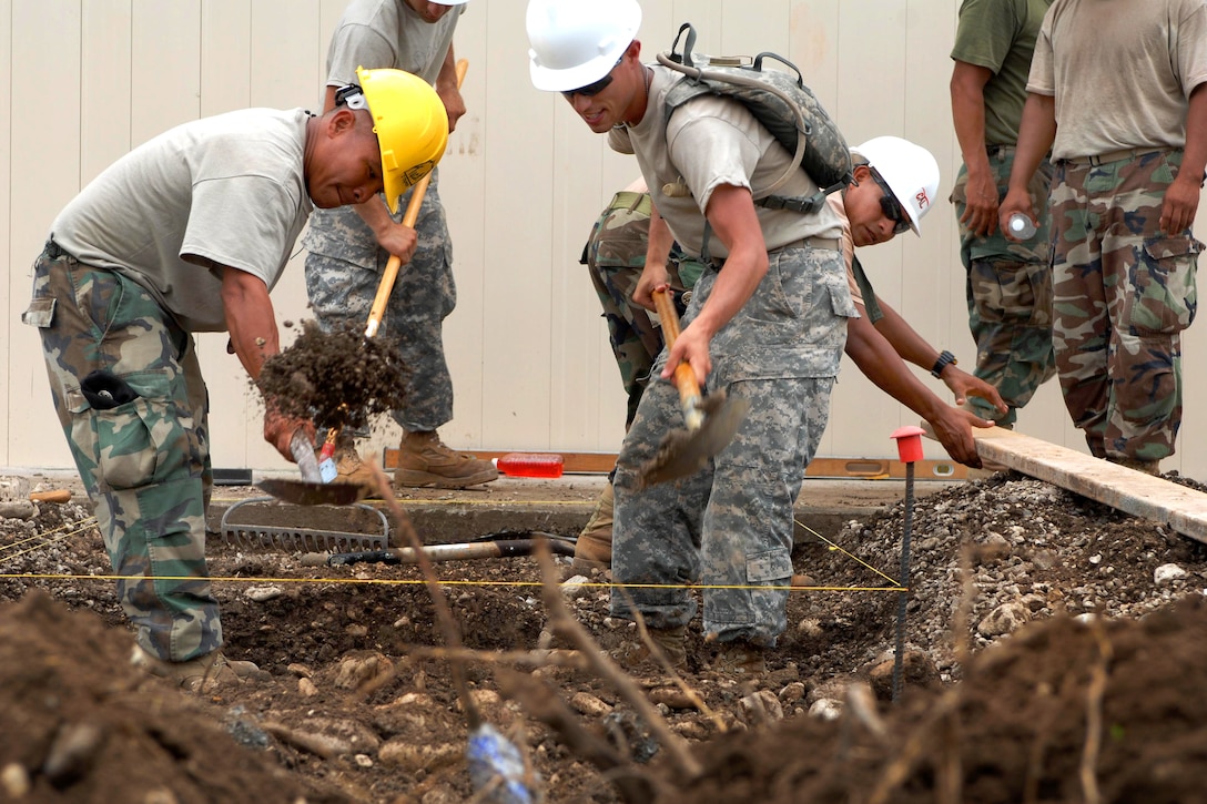 Belize Defense Force Pvt. Erasmo Teck, left, and U.S. Army Spc. Eric Kenton, right, dig the foundation for a concrete walkway at a school construction project in Upper Poteau, Haiti, June 3, 2011. Kenton and 57 other U.S. Army Reserve soldiers assigned to the 716th Engineer Company teamed up with Belizean Defense Force engineers in Haiti to help build two medical clinics, a school, and one latrine facility as part of Task Force Bon Voizen, or Good Neighbor. The U.S. Southern Command is sponsoring and U.S. Army South is conducting the joint foreign military humanitarian exercise under the command of the Louisiana National Guard.
