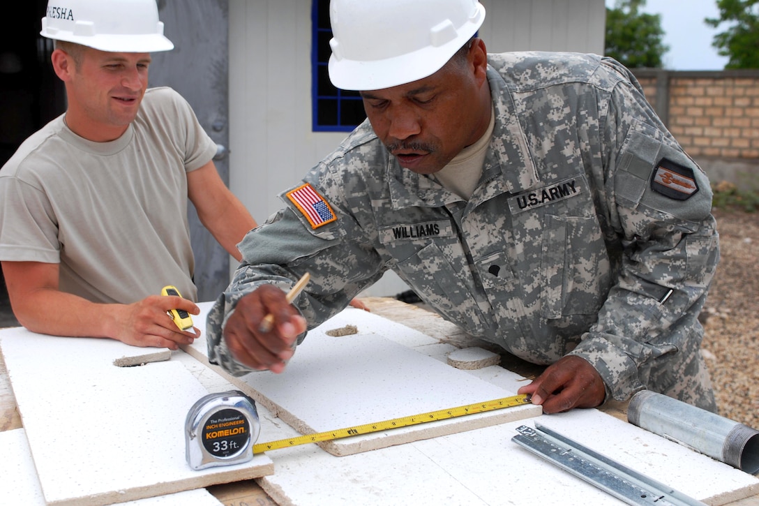 U.S. Army Spcs. Michael Ranucci, left, and Mark Williams, right, prepare ceiling tiles for installation at a medical clinic construction site in Haiti, June 2, 2011. Ranucci and Williams are assigned to the 716th Engineer Company.