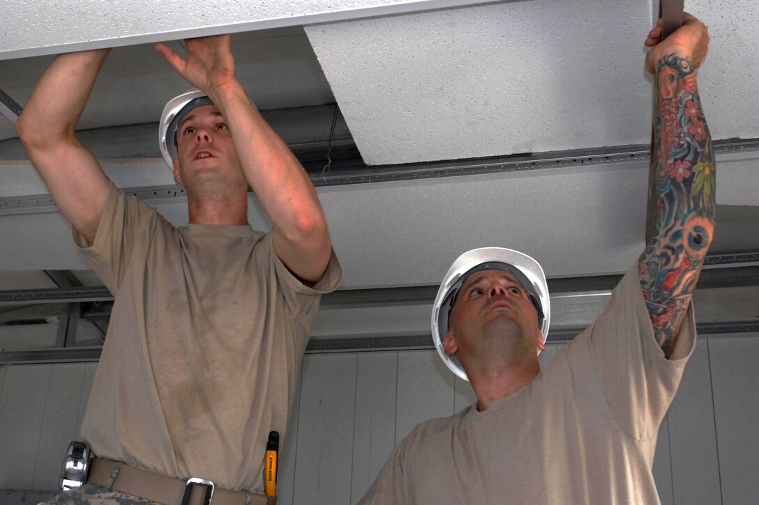 U.S. Army Spcs. Michael McGovern, left, and William Dudley, right, install a drop ceiling during a medical clinic construction project in Haiti, May 29, 2011. McGovern and Dudley are assigned to the 716th Engineer Company.
