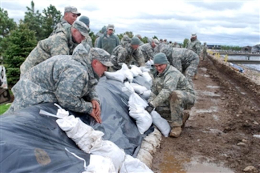 U.S. Army Sgt. Aaron Pallansch (right) uses sandbags to secure a plastic tarp to the top of a dike at Mandan's Waste Water Treatment Plant in Mandan, N.D., on May 31, 2011.  Pallansch is assigned to the North Dakota National Guard.  