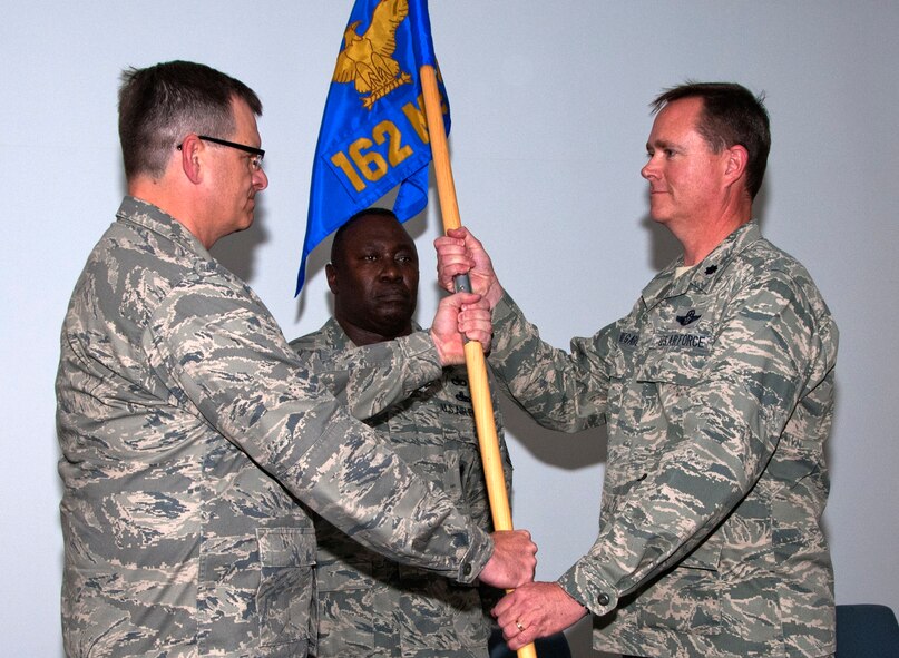 Col. Mick McGuire, left, 162nd Fighter Wing commander, passes the 162nd Mission Support Group flag to Lt. Col. Garry Beauregard as a symbol of his assumption of command June 4. The group consists of about 400 Airmen who support the international F-16 pilot training mission at Tucson International Airport. (U.S. Air Force photo/Master Sgt. Dave Neve)