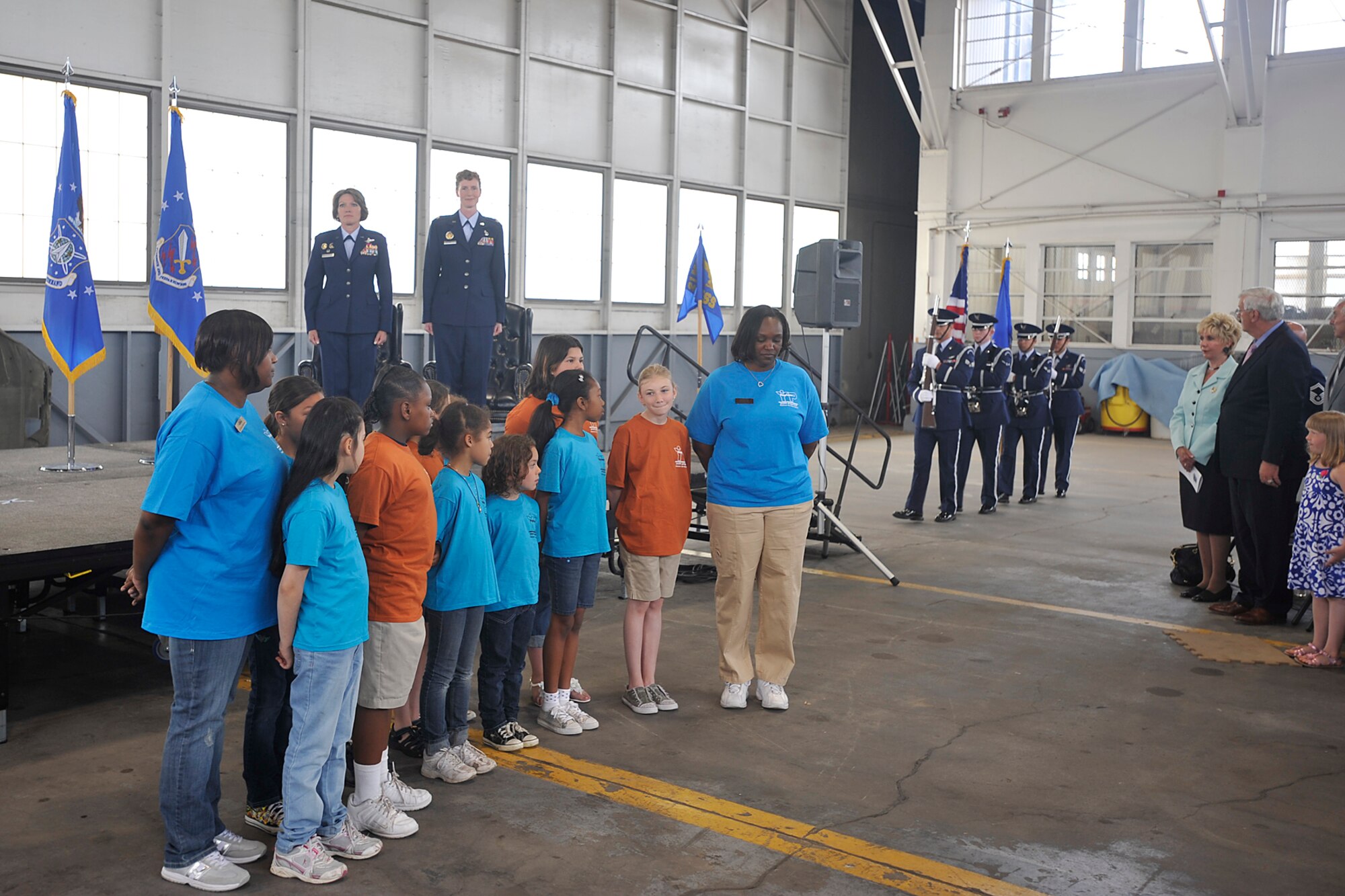 PETERSON AIR FORCE BASE, Colo. – The High Frontier Honor Guard makes its way to the stage to present colors June 2, 2011, for the 21st Force Support Squadron assumption of command ceremony in Hangar 133. Col. Kimerlee Conner, 21st Mission Support Group, (left, on stage), welcomed Lt. Col. Ann Igl, (right), as the 21st FSS commander. A group of children from the R.P. Lee Youth Center, part of the 21st FSS, sang “The Star-Spangled Banner” for a full house, including Colonel Igl’s family. (U.S. Air Force photo/Dennis Howk)
