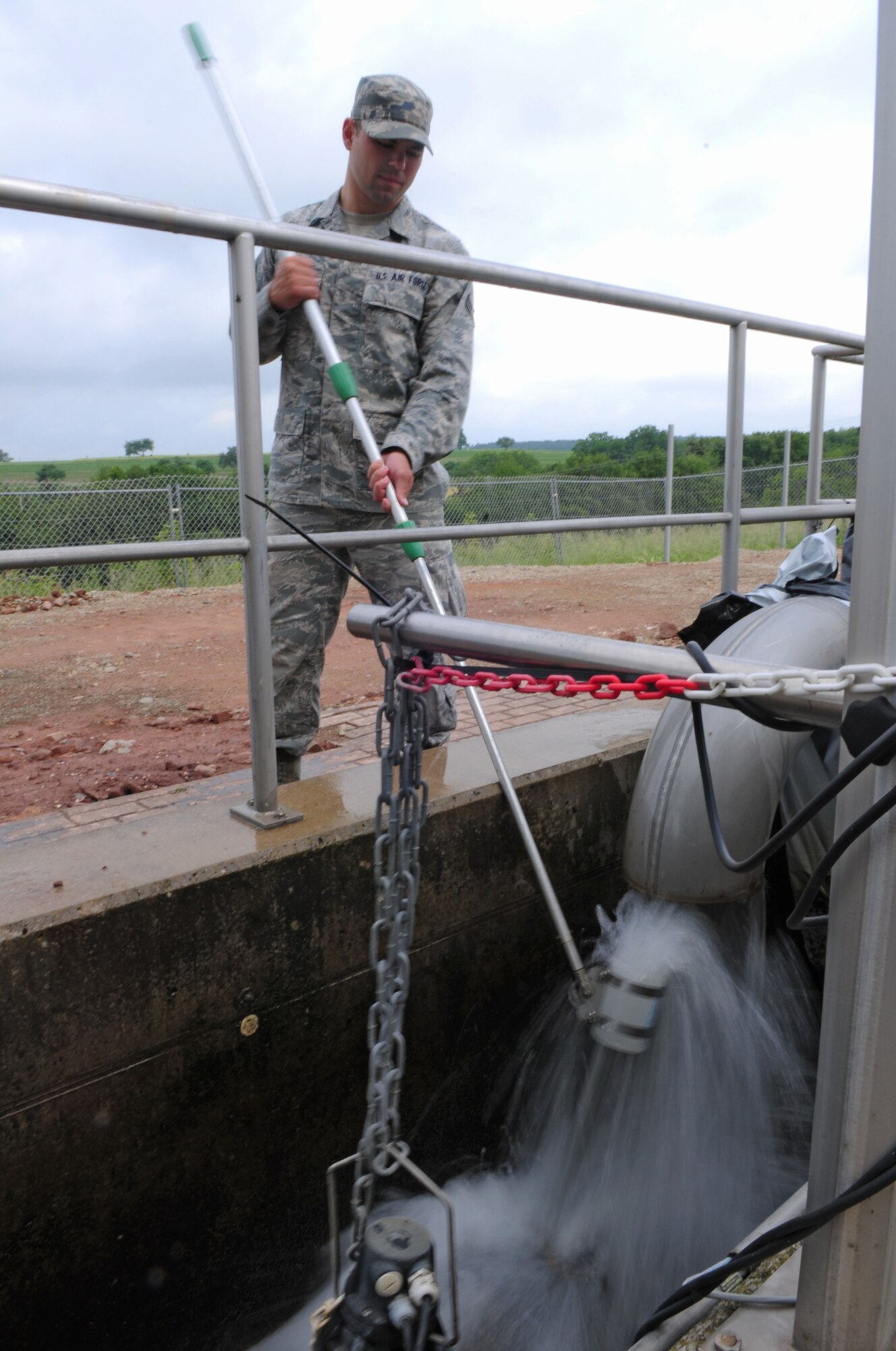SPANGDAHLEM AIR BASE, Germany – Airman 1st Class Andrew Herget, 52nd Civil Engineer Squadron water and fuel systems maintenance apprentice, collects a sample from the outflow water at the water treatment facility here June 6. The facility processes wastewater from the base to remove hazardous chemicals before it is released back into the environment. (U.S. Air Force photo/Airman 1st Class Matthew B. Fredericks)
