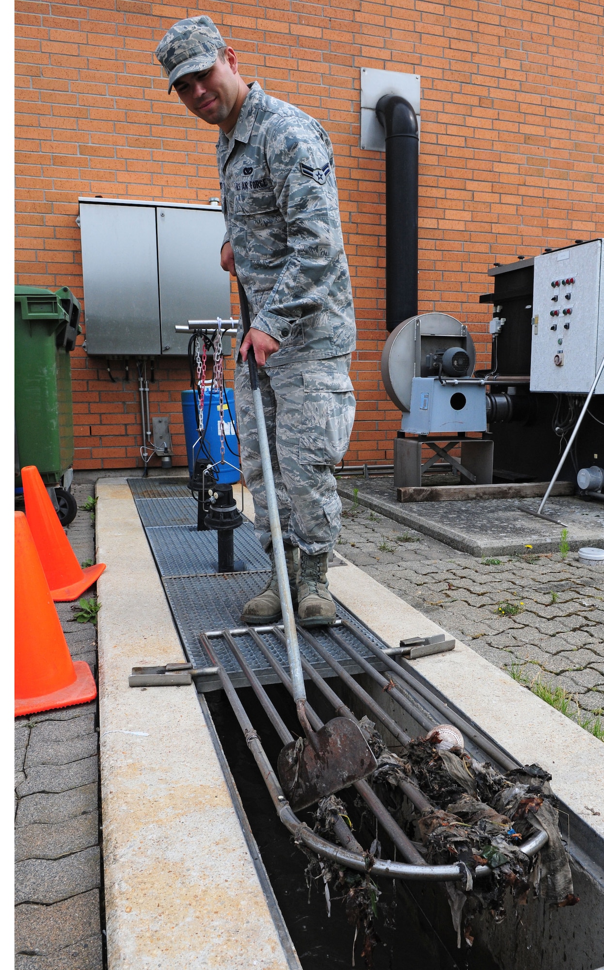 SPANGDAHLEM AIR BASE, Germany – Airman 1st Class Andrew Herget, 52nd Civil Engineer Squadron water and fuel systems maintenance apprentice, clears debris from an inflow grate at the water treatment facility here June 6. The facility processes wastewater from the base to remove hazardous chemicals before it is released back into the environment. (U.S. Air Force photo/Airman 1st Class Matthew B. Fredericks)
