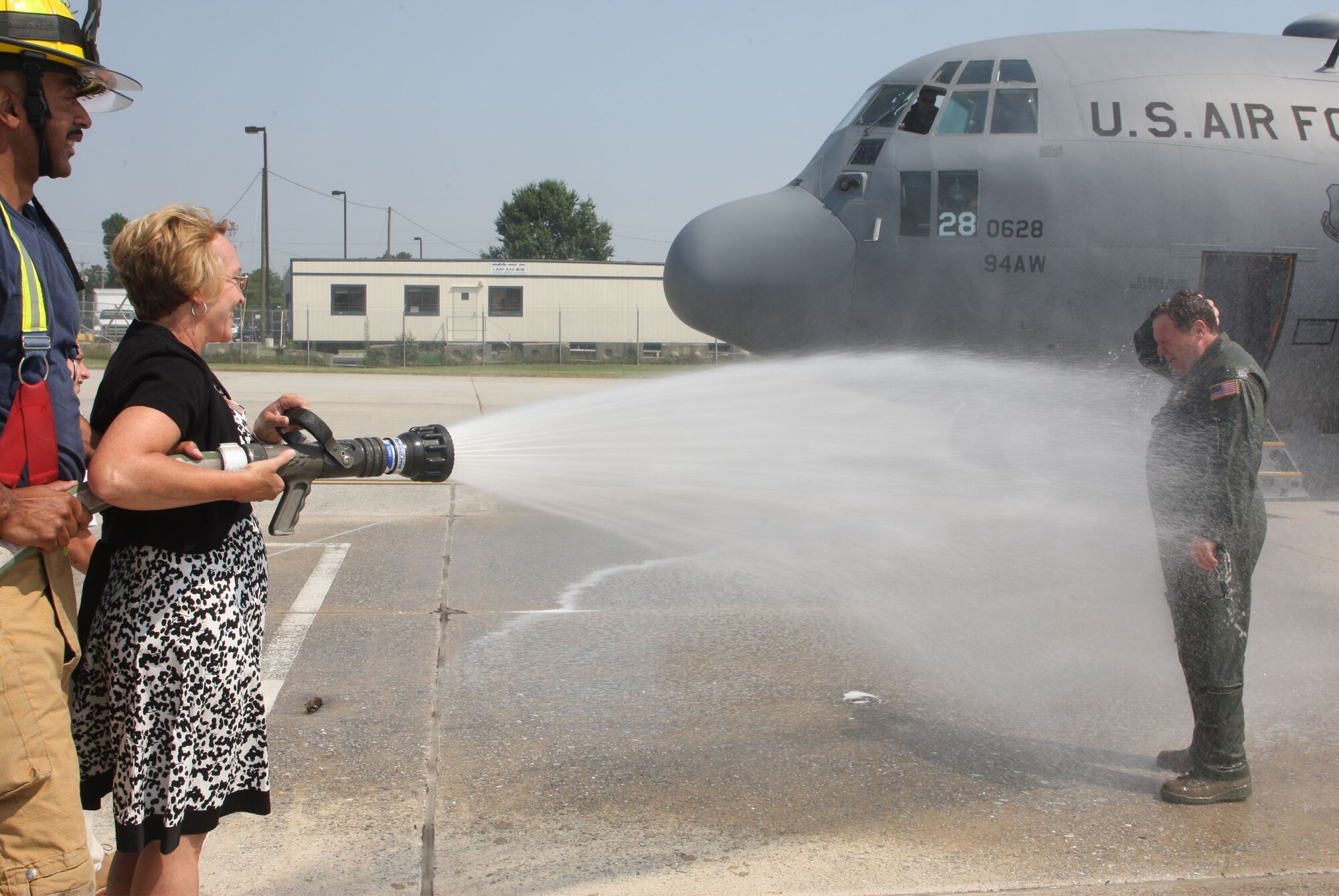 Anita Dodd, wife of Lt. Col. James M. Dodd, with the assistance of the Dobbins Fire Department soaks her husband as he steps out of the C-130 he piloted for his final flight June 4. (U.S. Air Force Photo/Don Peek)