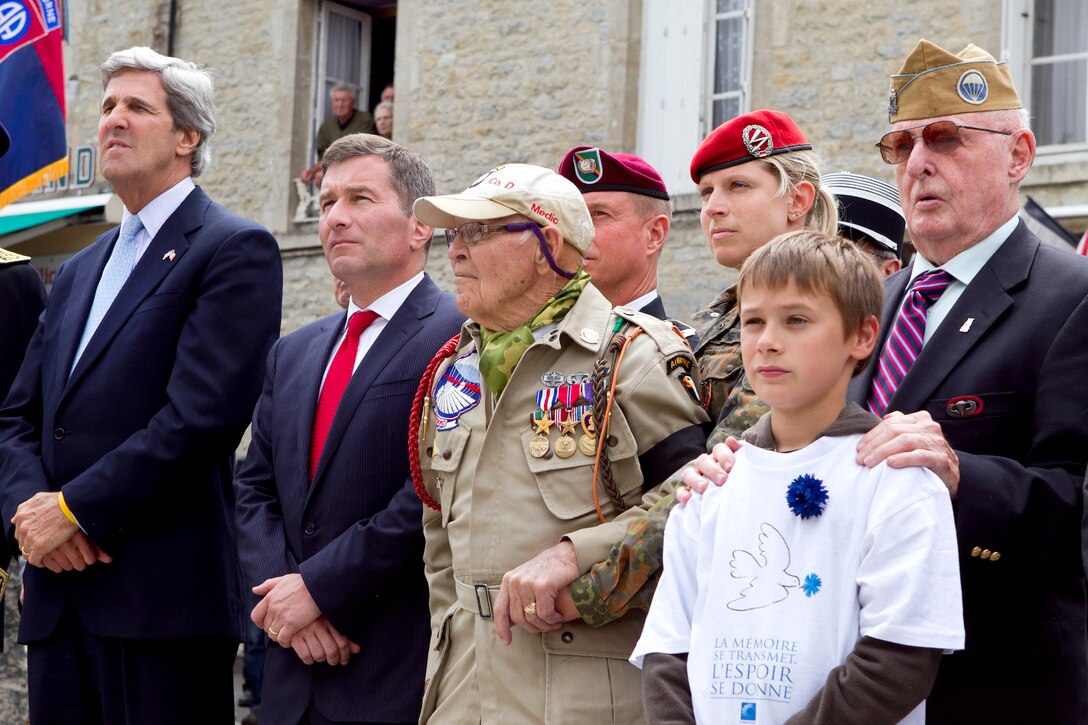 A German soldier helps support World War II veteran U.S. Army paratrooper Robert Wright as he prepares to receive the French Legion of Honor medal during a ceremony in Sainte Mere Eglise, France, June 6, 2011. Wright is receiving the medal for his heroics as a medic during WWII's D-Day invasion. U.S. Sen. John Kerry of Massachusetts, far left, stands with Wright as he waits for the medal.