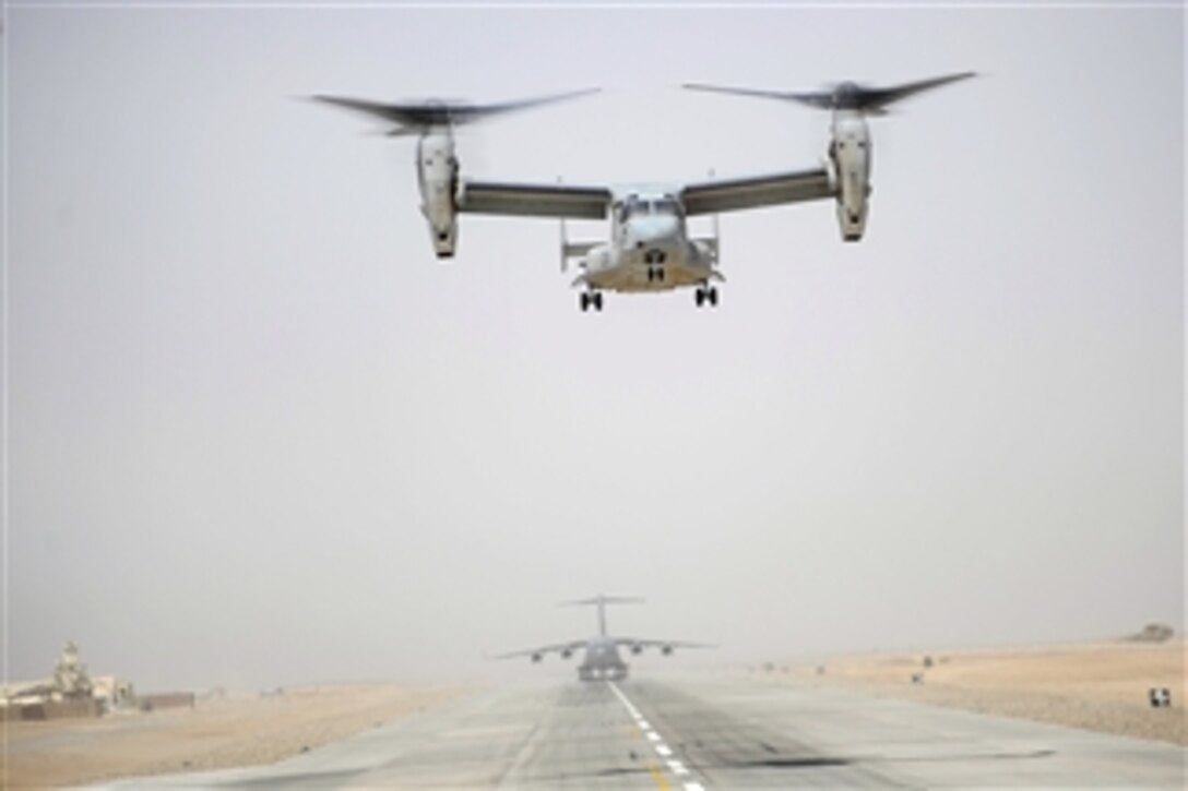 A U.S. Marine Corps MV-22 Osprey aircraft lands at a forward operating base in Afghanistan while a U.S. Air Force C-17 Globemaster III aircraft waits to take off on June 5, 2011.  