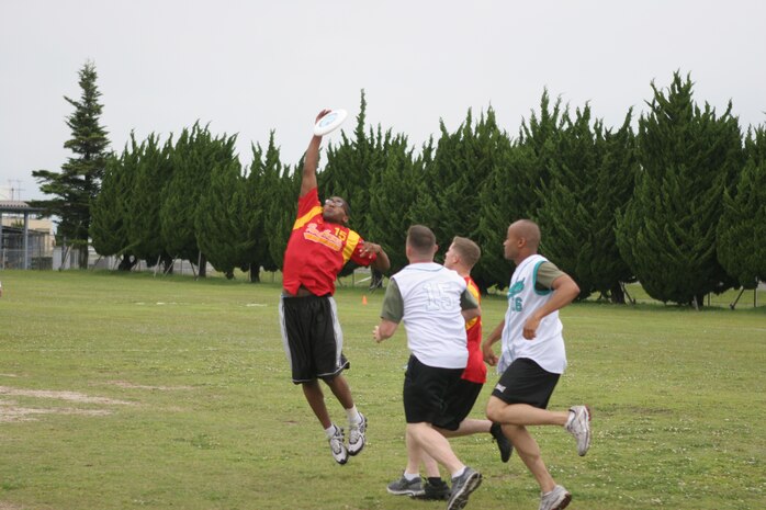 Edwin F. Jackson, a Marine Aircraft Group 12 Frisbee player, leaps to catch the Frisbee as several Marine Aviation Logistics Squadron 12 players attempt to stop him during the 2011 Commander’s Cup Ultimate Frisbee Tournament at Penny Lake Field here June 8. Throughout the tournament Jackson often wholly committed himself to making the catch, several times colliding with opposing players. MAG-12 went on to win the game 11-7.