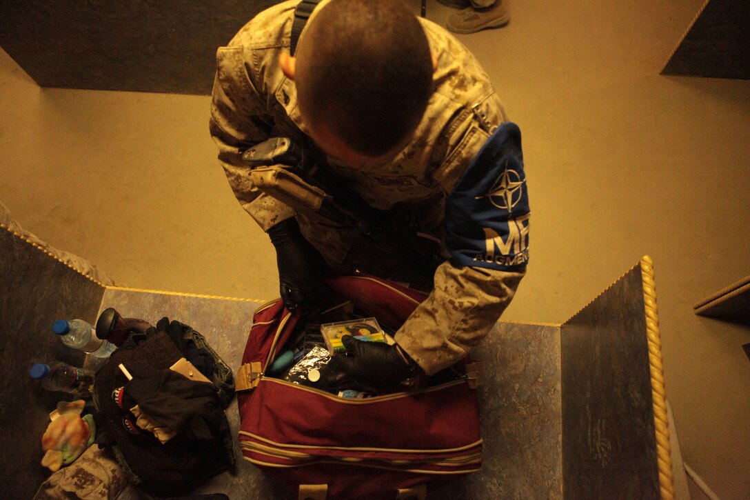 Lance Cpl. Richard Carr, a Marine Attack Squadron 513 airframe mechanic and Durham, N.C., native, sorts through an incoming passenger’s personal effects at Kandahar Airfield, Afghanistan, June 8.
