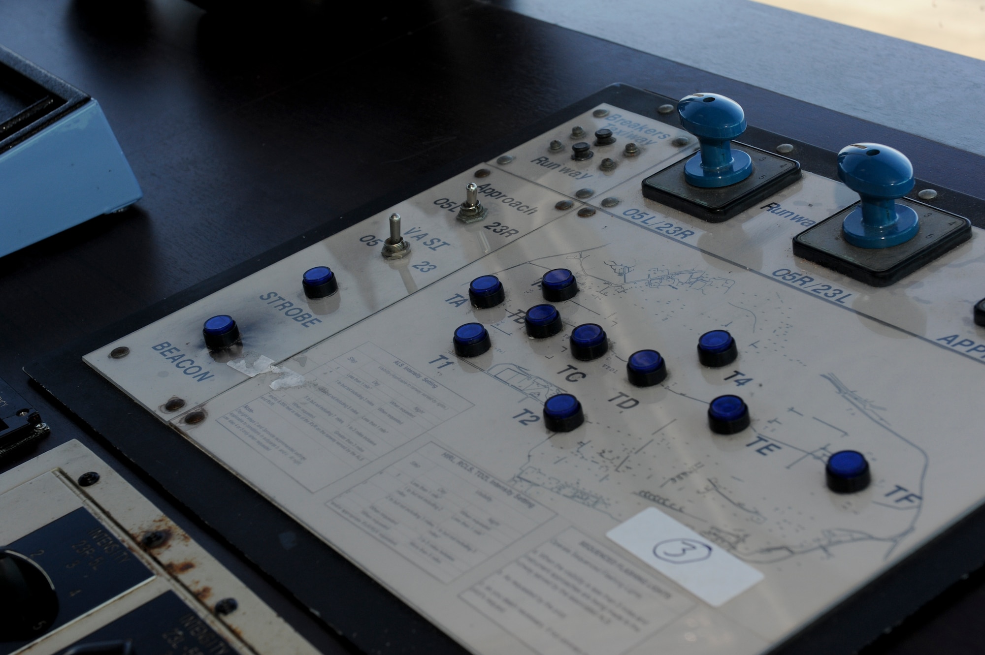 Controllers use the lighting panel to adjust lighting based on weather and visibility requirements as outlined by the Federal Aviation Administration, June 7.  The blue buttons operate the taxiway lighting across the airfield and the large "T" handles operate the lights on the runway. (U.S. Air Force photo/ Airman 1st Class Brooke Beers)