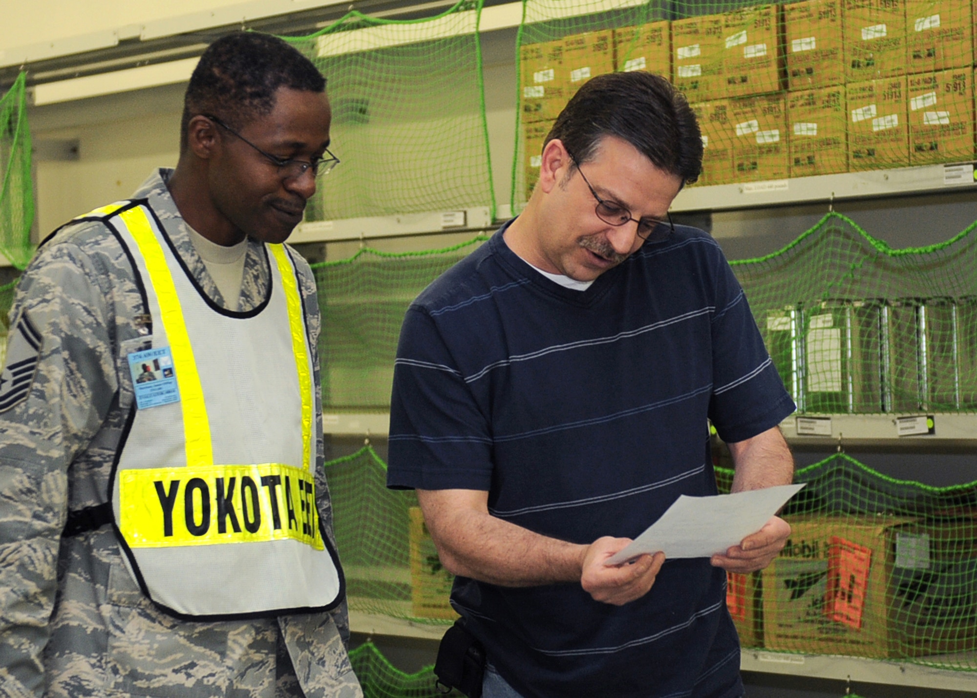 YOKOTA AIR BASE, Japan -- Senior Master Sgt. James Morrison (left), 374th Logistics Readiness Squadron exercise evaluation team member, observes as Gary Furman, 374th LRS supply technician, reads a hazardous material scenario during the Initial Readiness Response Exercise at Yokota Air Base, June 8, 2011. The goal of the exercise was to test Yokota's ability to respond appropriately and effectively to real world contingencies. (U.S. Air Force photo/Senior Airman Andrea Salazar)