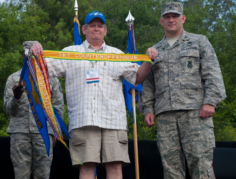 MOODY AIR FORCE BASE, Ga. -- Retired Sgt.  Roger Nelson, former 823rd Combat Security Police Squadron fire direction controller and Safeside Association treasurer, and Col. Randall Richert, 820th Base Defense Group commander, display a streamer earned by the 823rd CSPS during the Tet Offensive in 1968. (U.S. Air Force photo/Airman 1st Class Jarrod Grammel)(RELEASED)