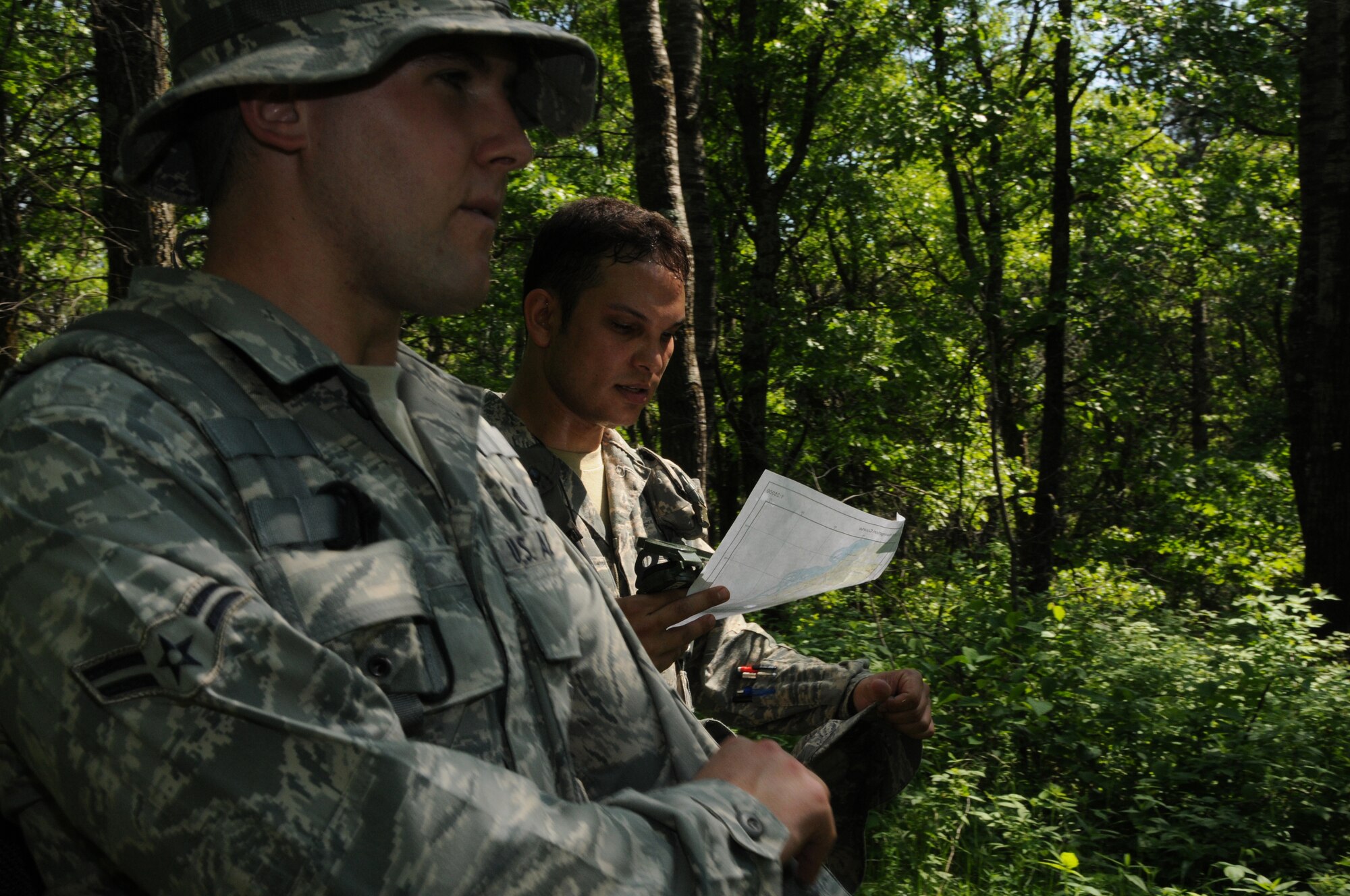 Staff Sergeant Mitch Pitoscia and Airman 1st Class Corey Pitoscia, members of the Security Forces Squadron, 148th Fighter Wing, Duluth, Minn., consult their map and compass as they make their way through the land navigation course at Camp Ripley, Minn. on June 5, 2011.  The land navigation course tests the ability to plot out a course prior to entering the woods, but also the ability to stay on that course despite difficult terrain.  (U.S. Air Force Photo by Tech. Sgt. Scott Herrington)